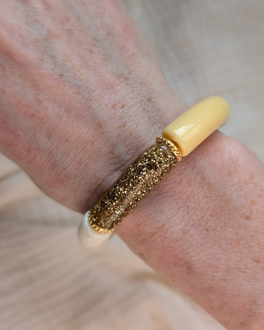 Bracelets perles tube jaune pastel Marie avec perles intercalaires dorées haute qualité. Porté au poignet d'une femme. Création La Tête dans les nétoiles