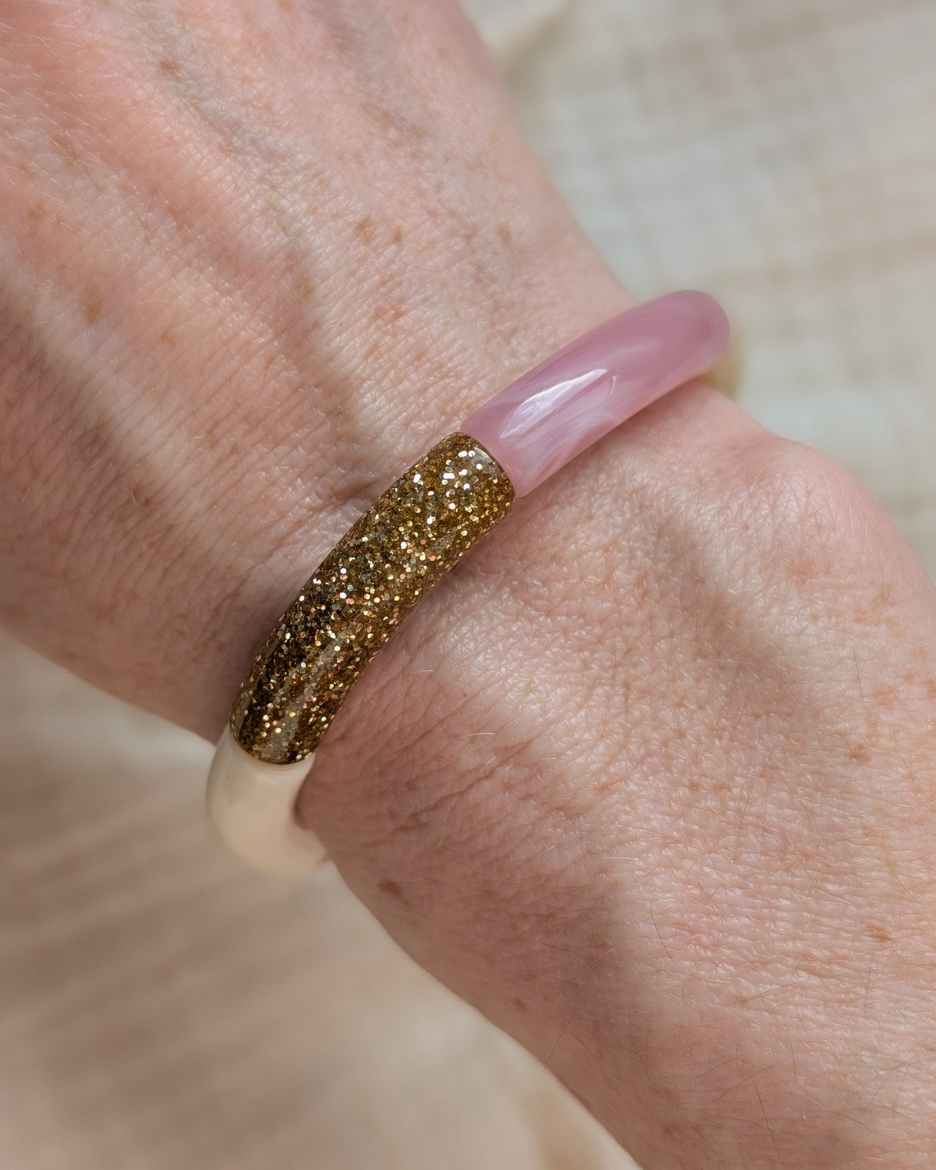 Gros plan sur bracelet Lisa perles tube rose tendre et glitter à paillettes dorées . Porté au poignet d'une femme. Création La Tête dans les Nétoiles