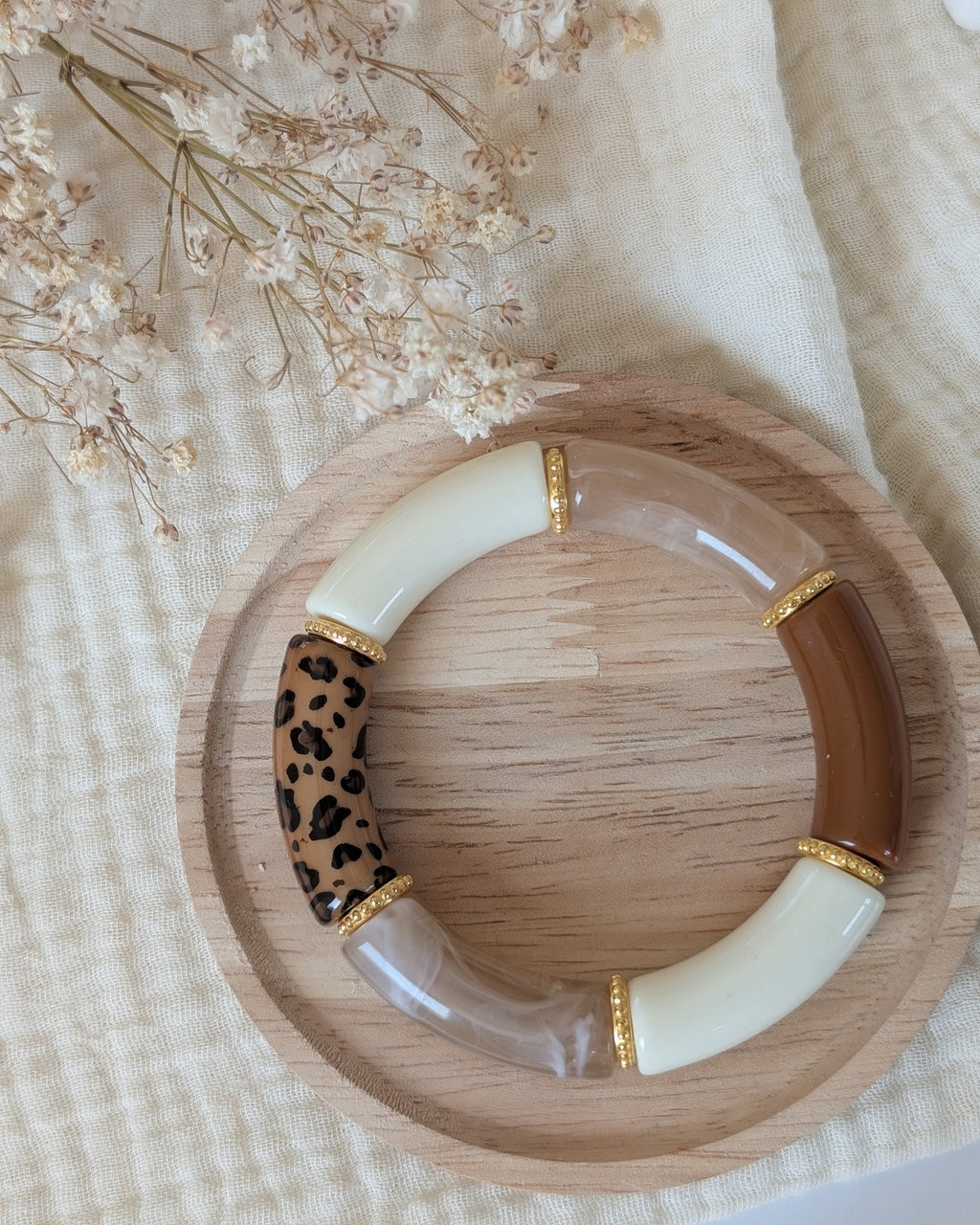 Bracelet perles tube Marie léopard tons naturels avec perles intercalaires dorées haute qualité. Posé sur support en bois. Création La Tête dans les Nétoiles