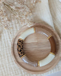 Bracelet perles tube Marie léopard tons naturels avec perles intercalaires dorées haute qualité. Posé sur support en bois. Création La Tête dans les Nétoiles