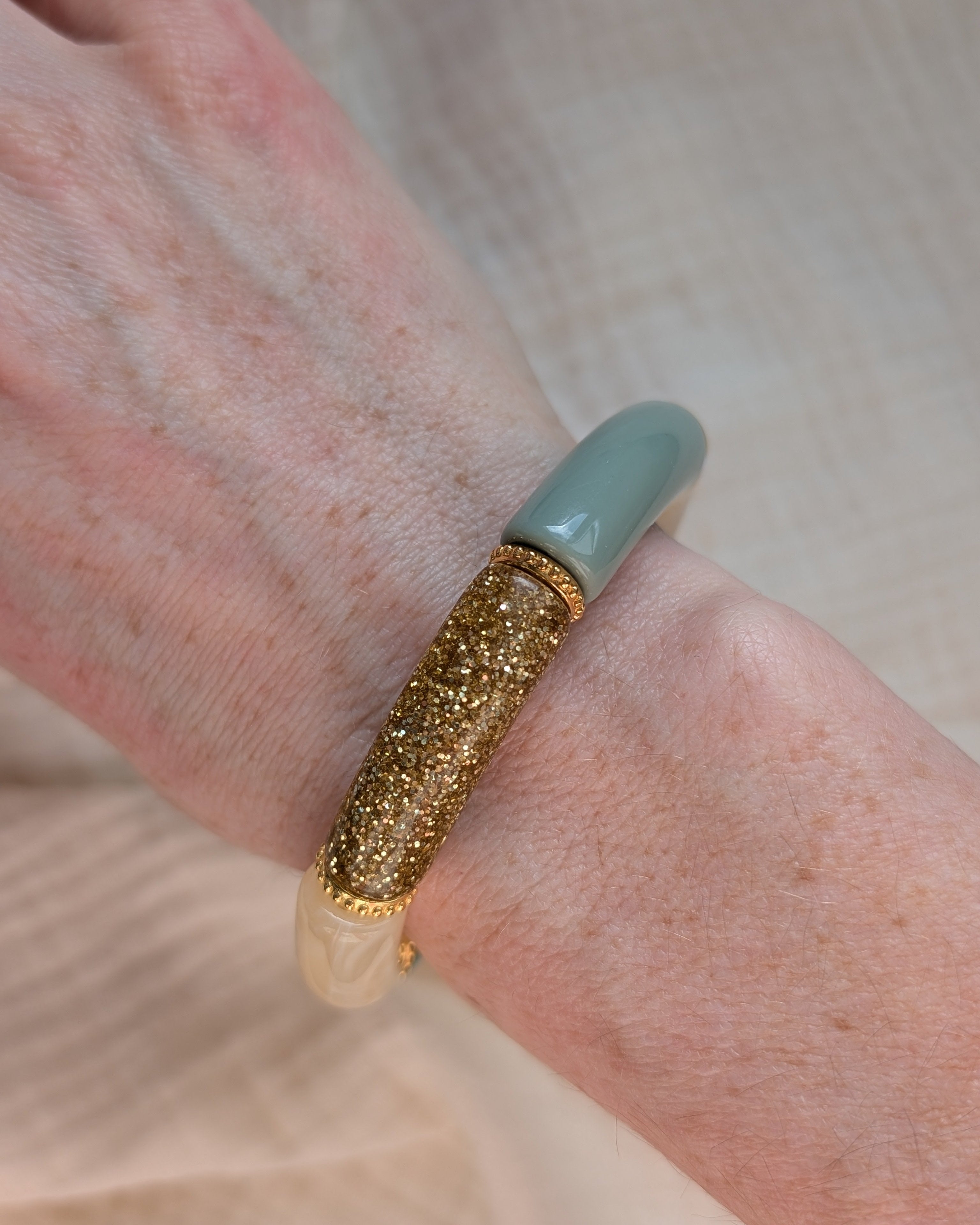 Bracelet perles tube Marie vert pastel et marbré avec perles intercalaires dorées haute qualité. Porté au poignet d'une femme. Création La Tête dans les Nétoiles