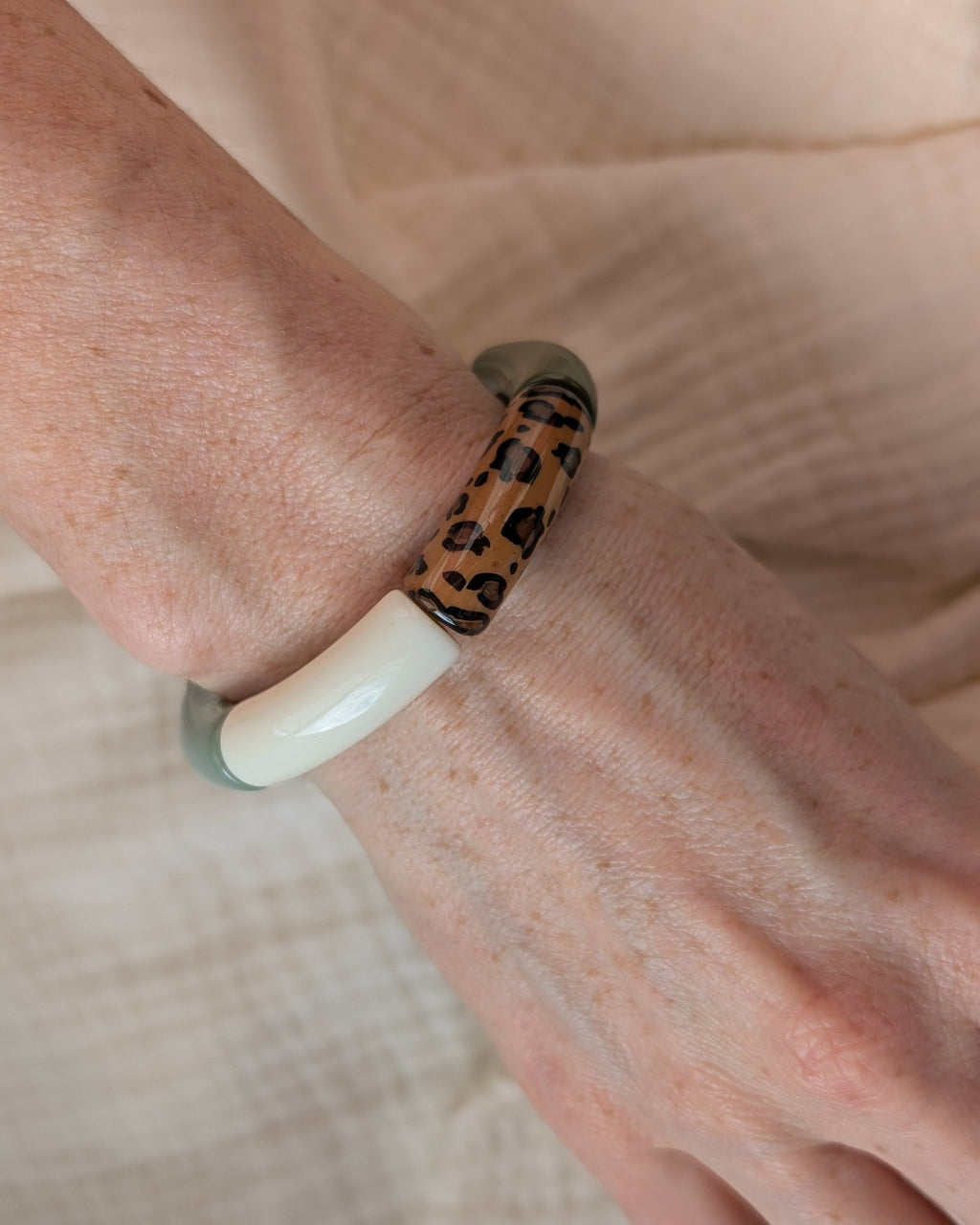 Bracelet perles tube mona leopard et vert porte sur poignet de femme. Création La Tête dans les Nétoiles