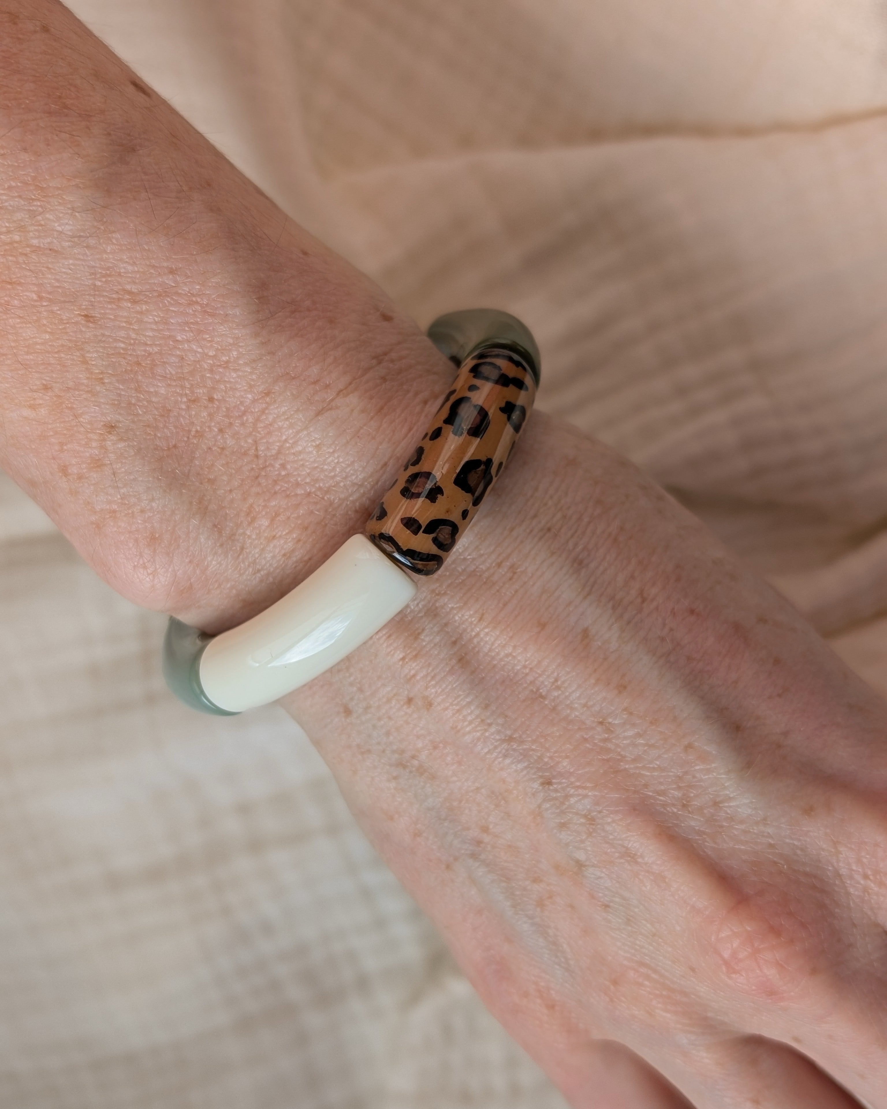 Bracelet perles tube mona leopard et vert porte sur poignet de femme. Création La Tête dans les Nétoiles
