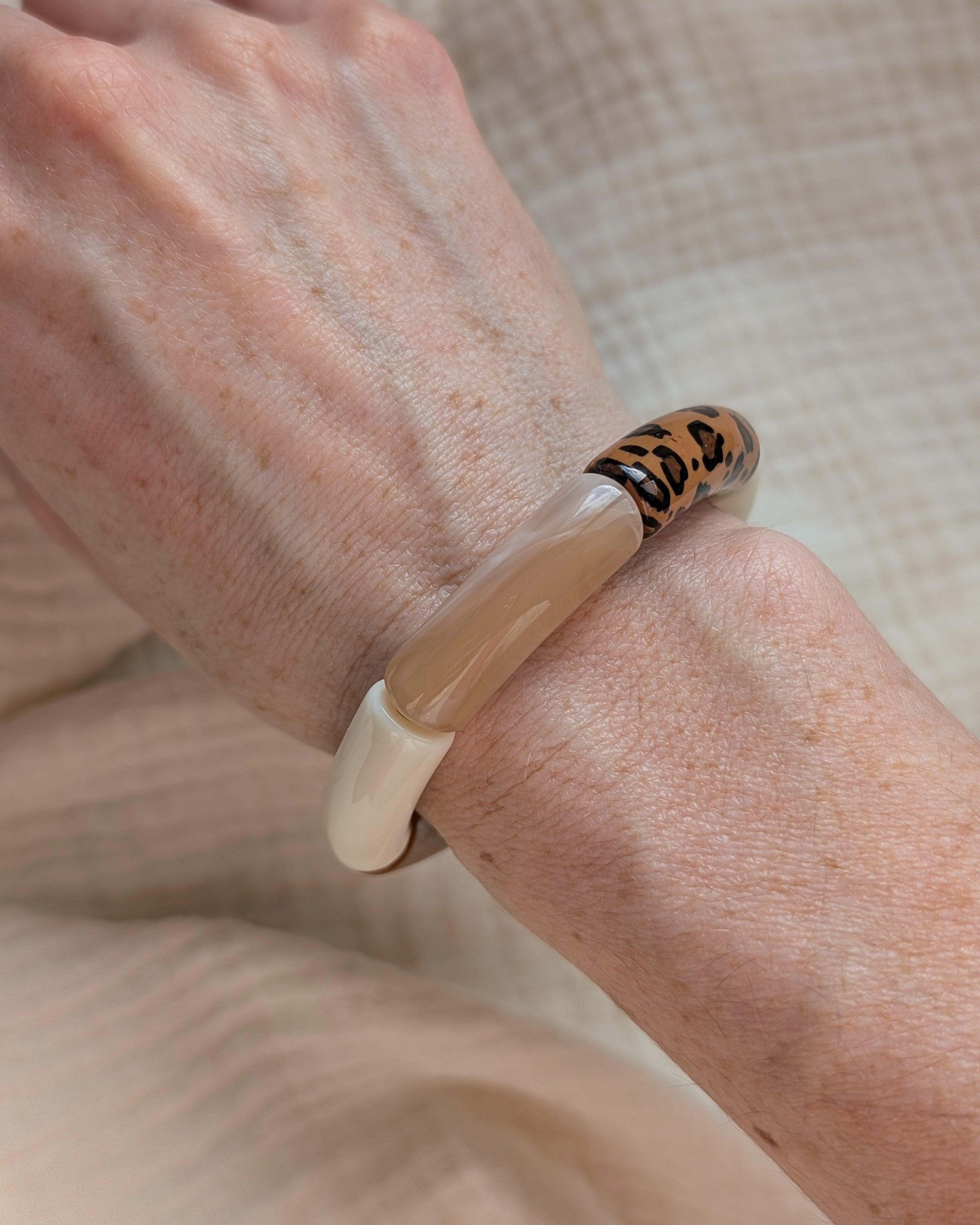 Bracelet perles tube mona ton naturel et leopard porté sur poignet de femme. réation La Tête dans les Nétoiles