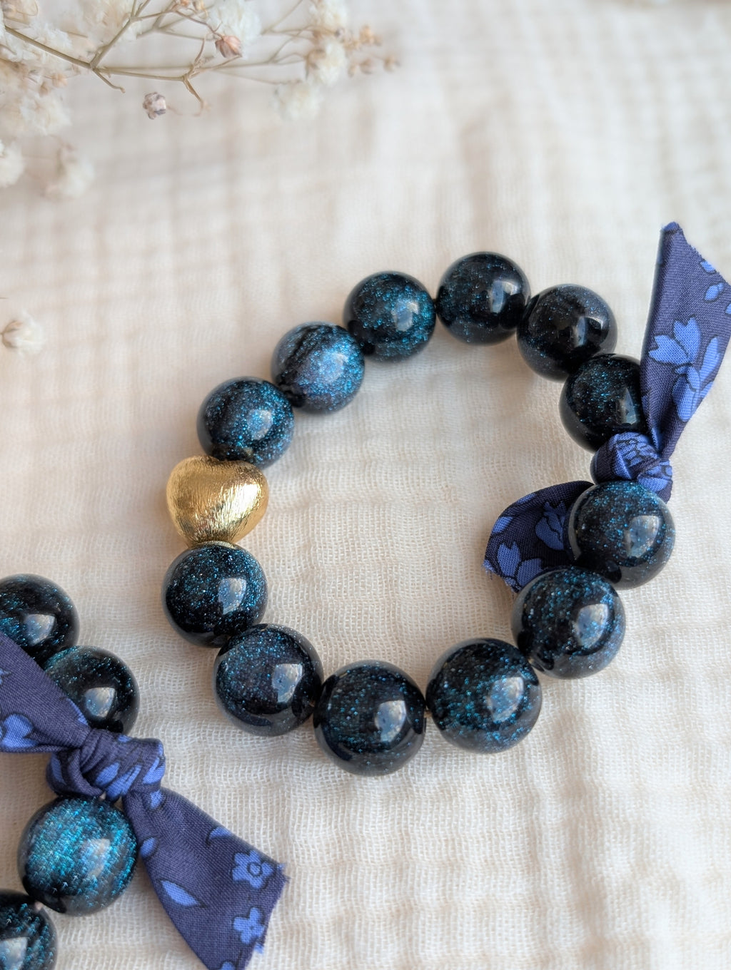 Bracelet personnalisé LIBERTY GLOWY perle en résine paillette bleu galaxy et perle coeur en or. Bijoux personnaisables La Tête dans les Nétoiles. 