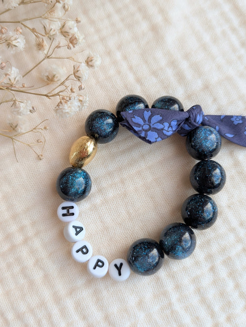 Bracelet LIBERTY GLOWY perles bleu nuit à paillettes avec mots doux duo mère fille. Perle en résine coeur en plaqué or. bijoux personnallisés. Mots HAPPY sur fond gaze de coton.Créations artisanales La Tête dans les Nétoiles