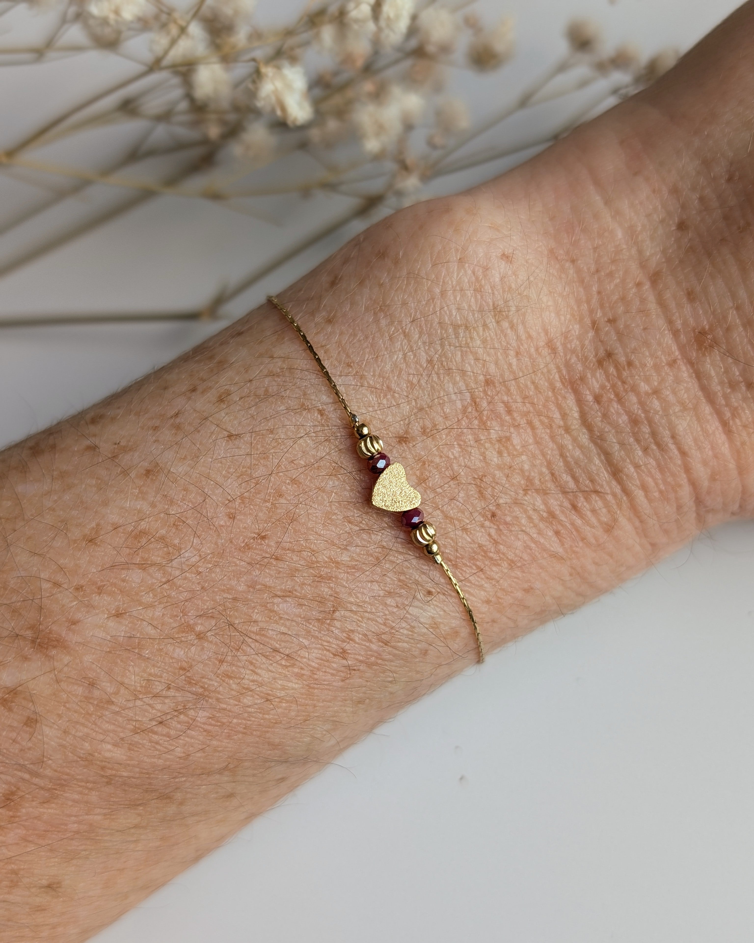 Bracelet  porté fin chaine maille serpentine en acier inoxydable doré et perle coeur diamanté et  en verre rouge irisé. Créations la Tête dans les Nétoiles