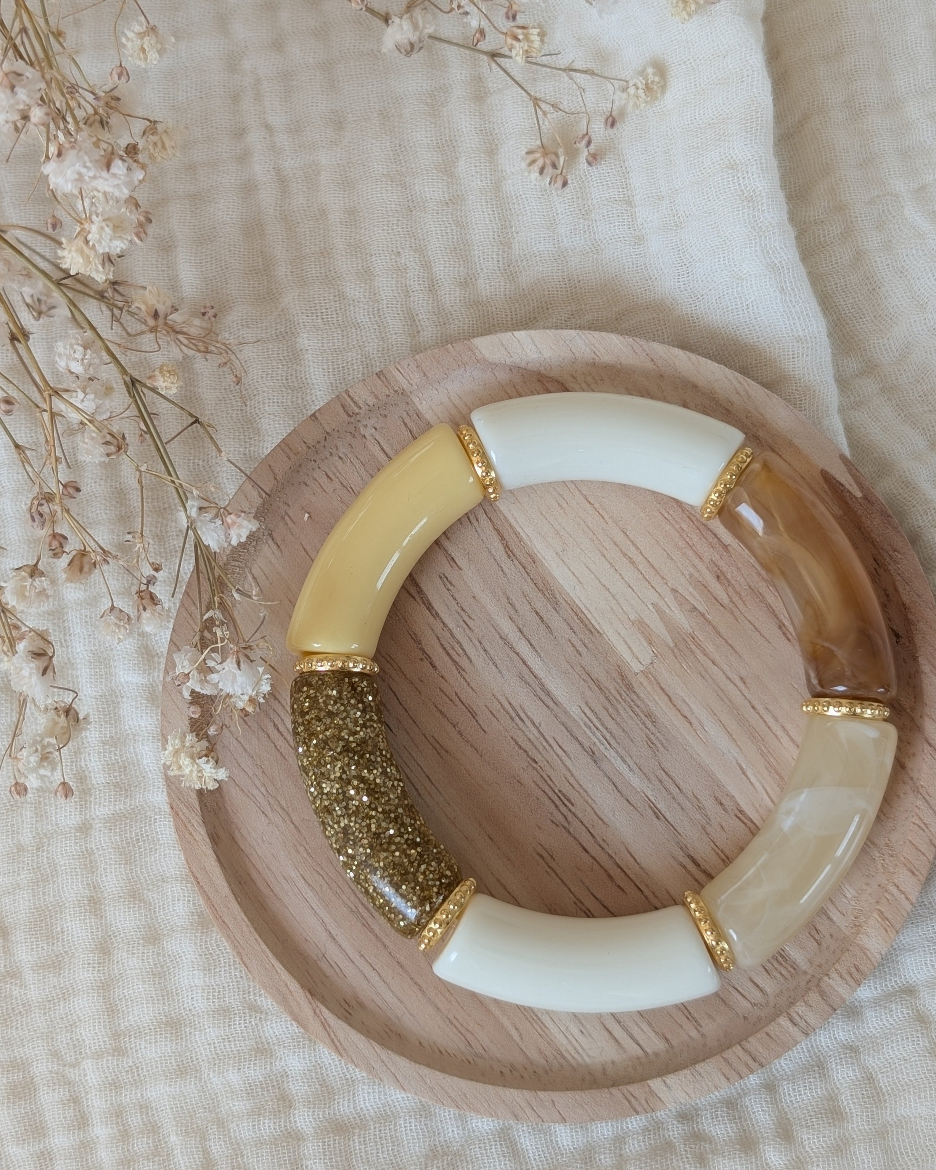 Bracelet perles tube marie jaune pastel avec intercalaires perles dorées hautes qualité. sur support en bois. Création La Tête dans les nétoiles