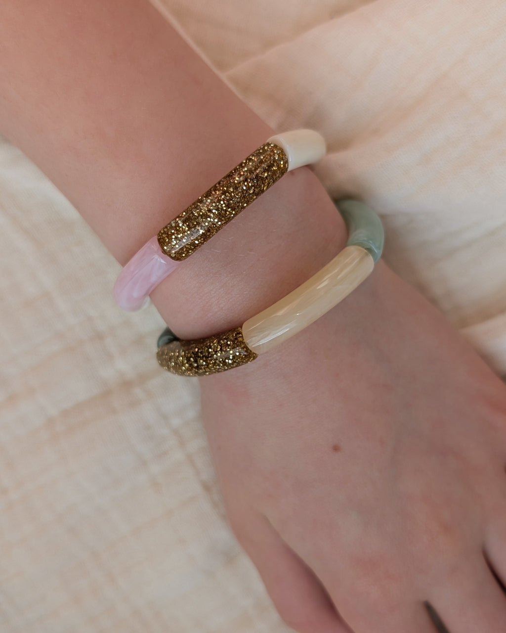 Duo de bracelets perles tube portés par une enfant. Gros plan sur les perles glitter à paillettes doré. Création La Tête dans les Nétoiles