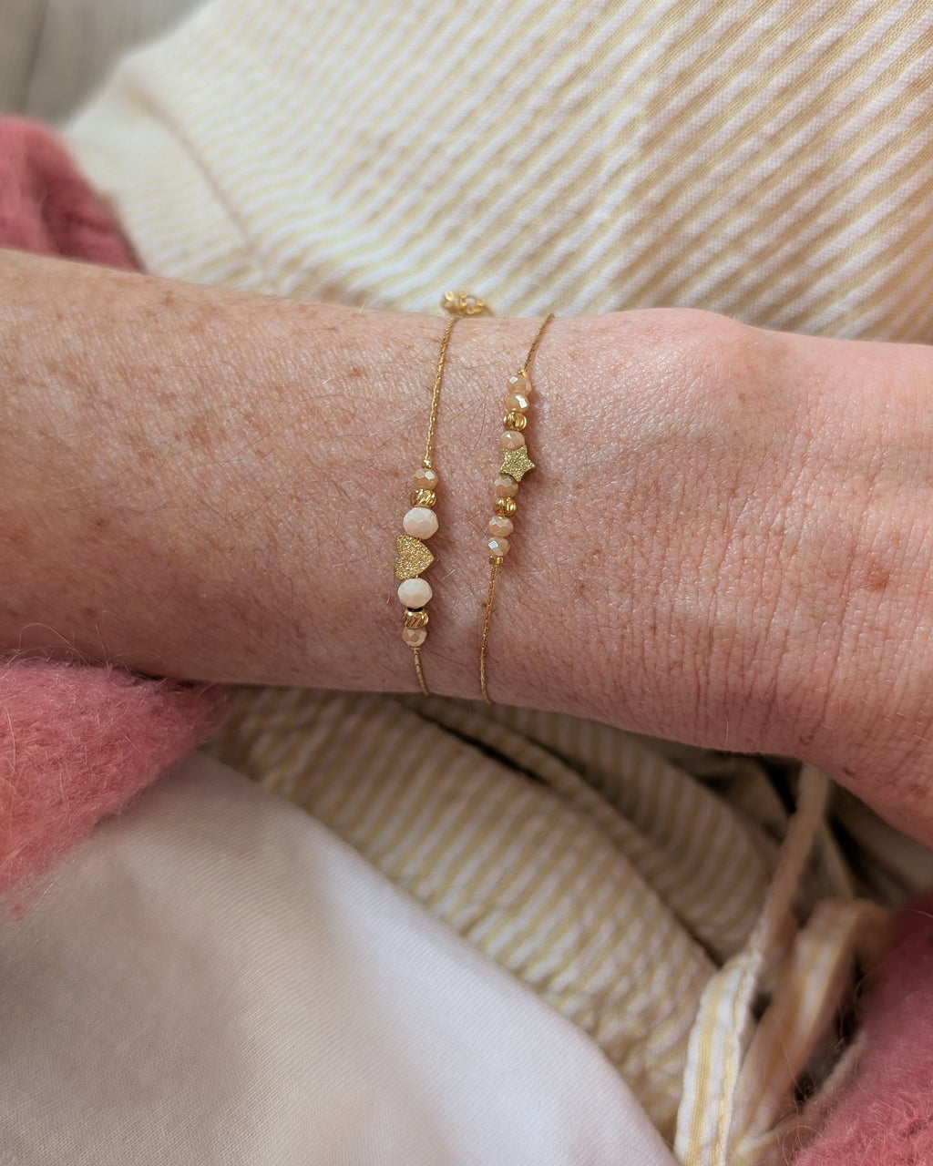 Bracelets fins les précieux portés par une femme. Un orné d'un coeur diamanté et l'autre orné d'une étoile diamantée. Création La Tête dans les Nétoiles
