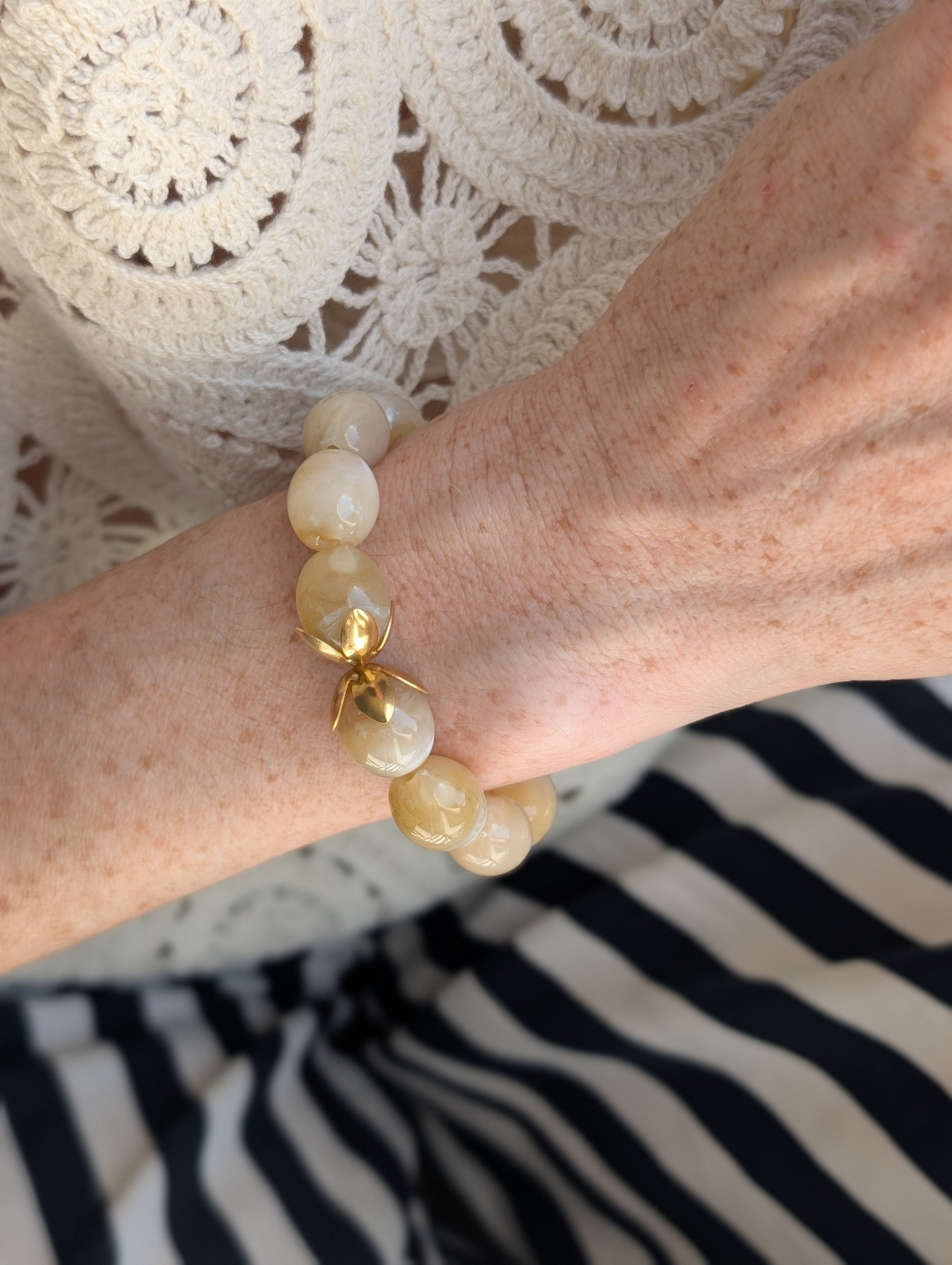 bracelet Olivia perles résine beige marbré porté par une femme avec un haut brodé. Créations artisanales La Tête dans les Nétoiles