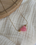 Collier Aimée perle coeur en résine rose tendre et acier inoxydable doré. Posé sur plateau en bois et gaze de coton écru. Créations faits main La Tête dans les Nétoiles