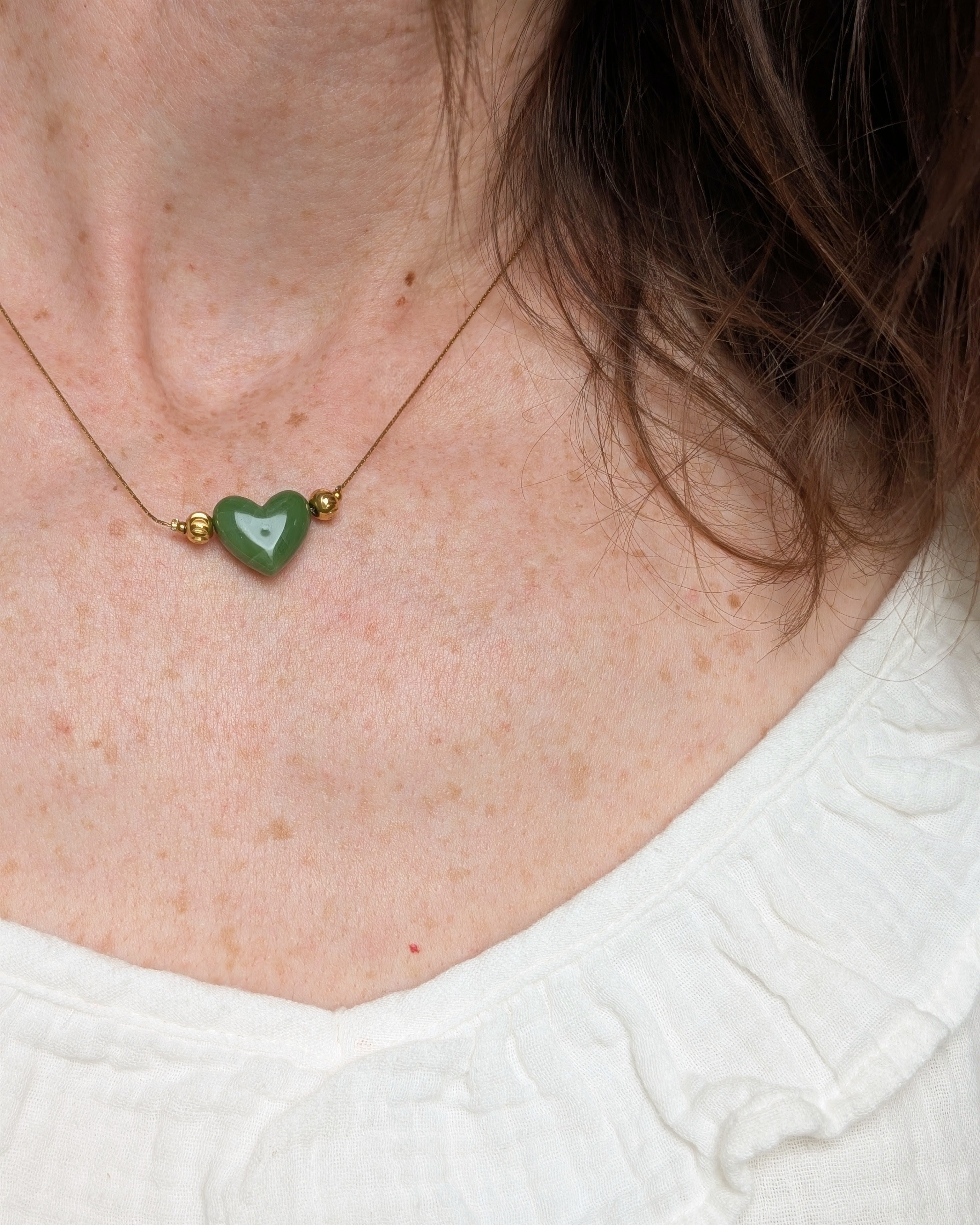 Collier Aimée perle coeur en résine vert kaki et acier inoxydable doré. Porté par une femme. Créations faits main La Tête dans les Nétoiles