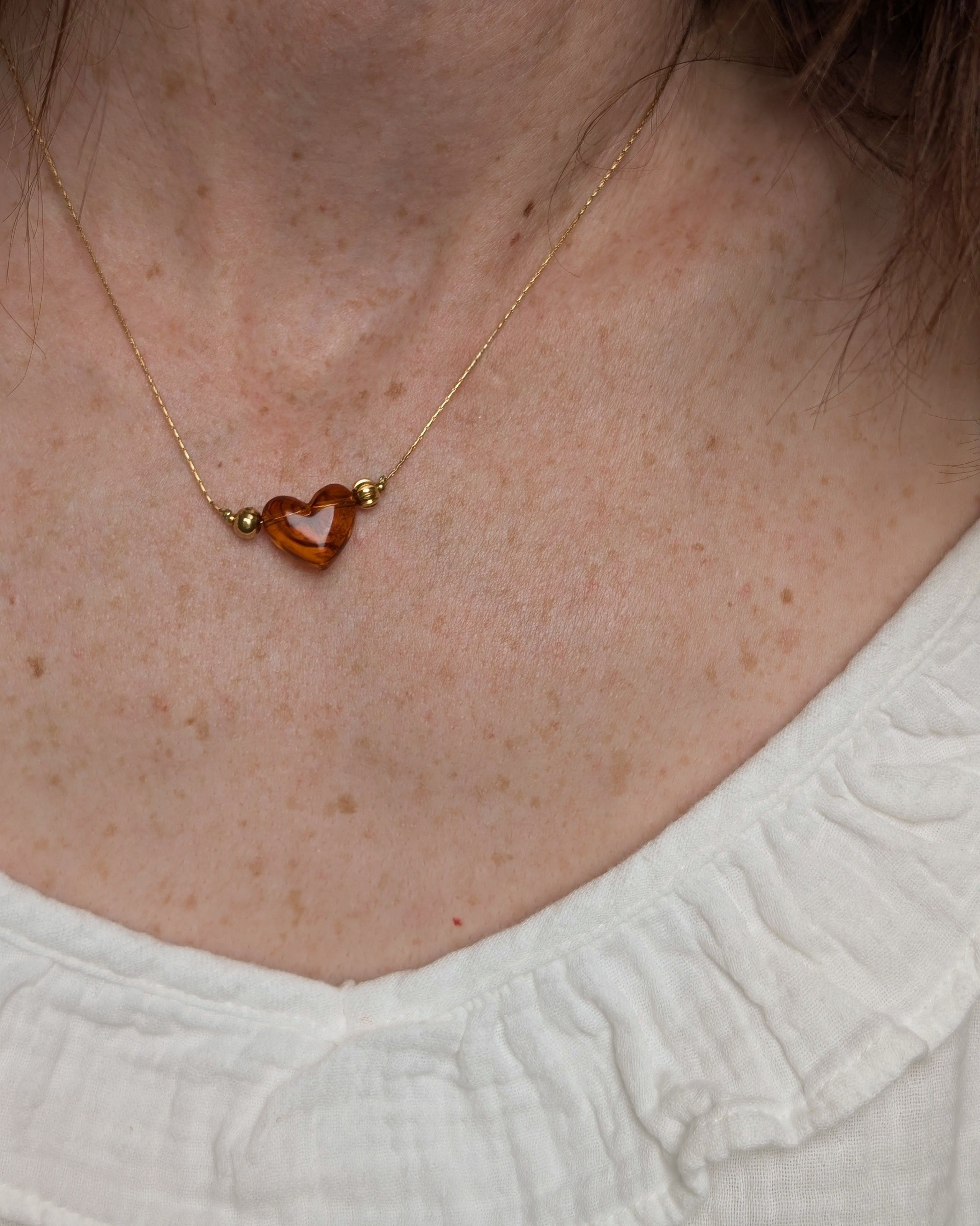 Collier Aimée perle en résine coloris ambré marbré porté par une femme. Créations artisanales La Tête dans Les nétoiles