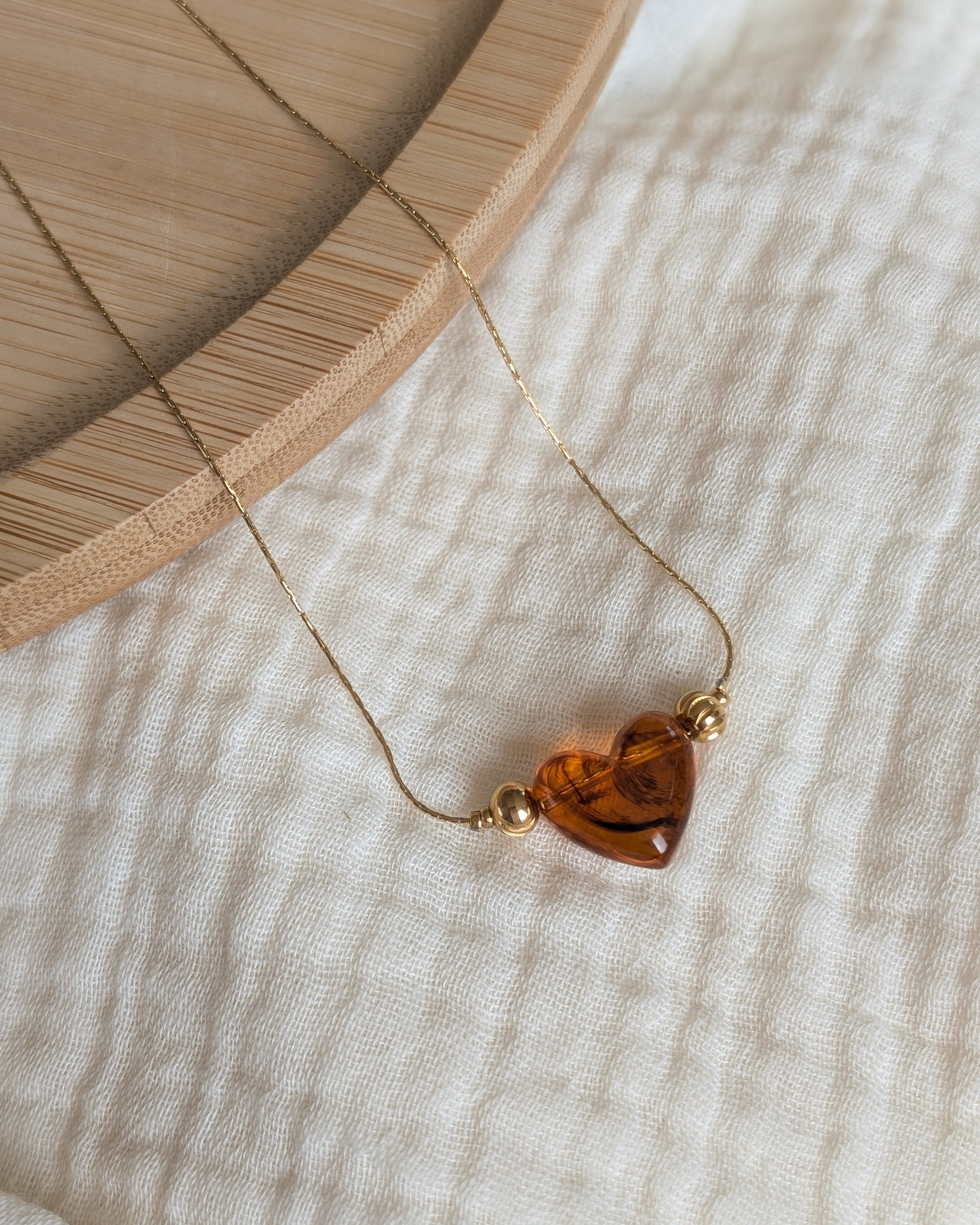Collier Aimée perle en résine coloris ambré marbré posé sur gaze de coton. Créations bijoux artisanales La Tête dans les Nétoiles.