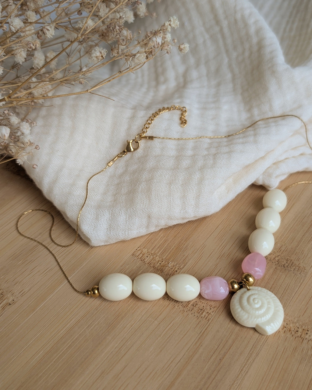 Collier Azura coquillage perles résine posé sur plateau en bois photo en entier avec fermoir en entier. Création artisanale La Tête dans les Nétoiles 