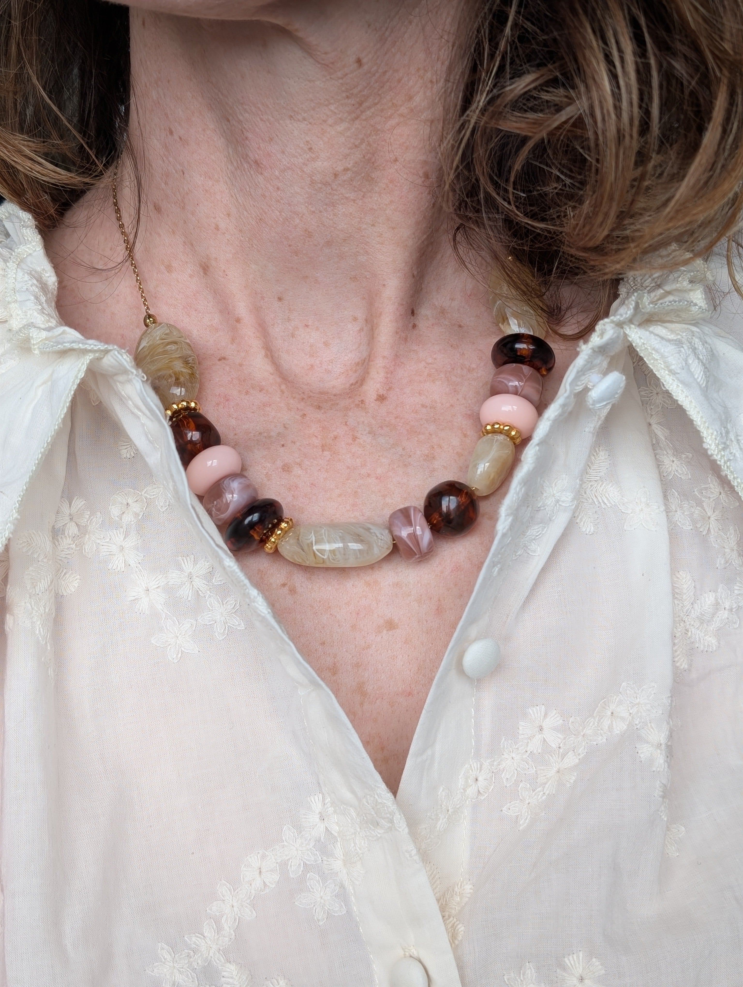 Collier GABIE perles ovales donuts perles irregulieres couleurs ambrée crème rose poudre nuances de rose perles irrégulières perles en résine . collier porté par une femme Création artisanale La Tête dans les Nétoiles