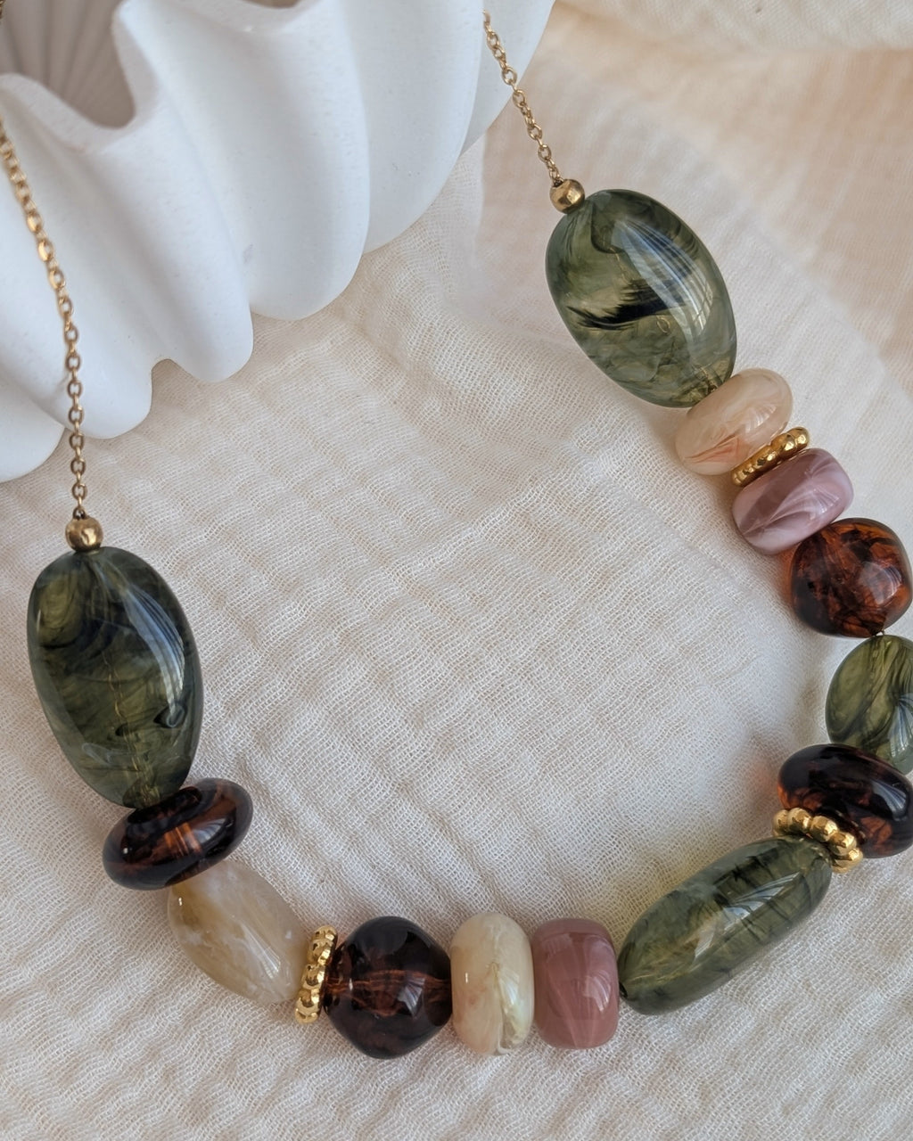 collier GABIE nuances de vert et d'ambre sur fond de gaze de coton. Perles en résine irrégulières enfilées sur chaîne maille forçat. Création artisanale La Tête dans les Nétoiles