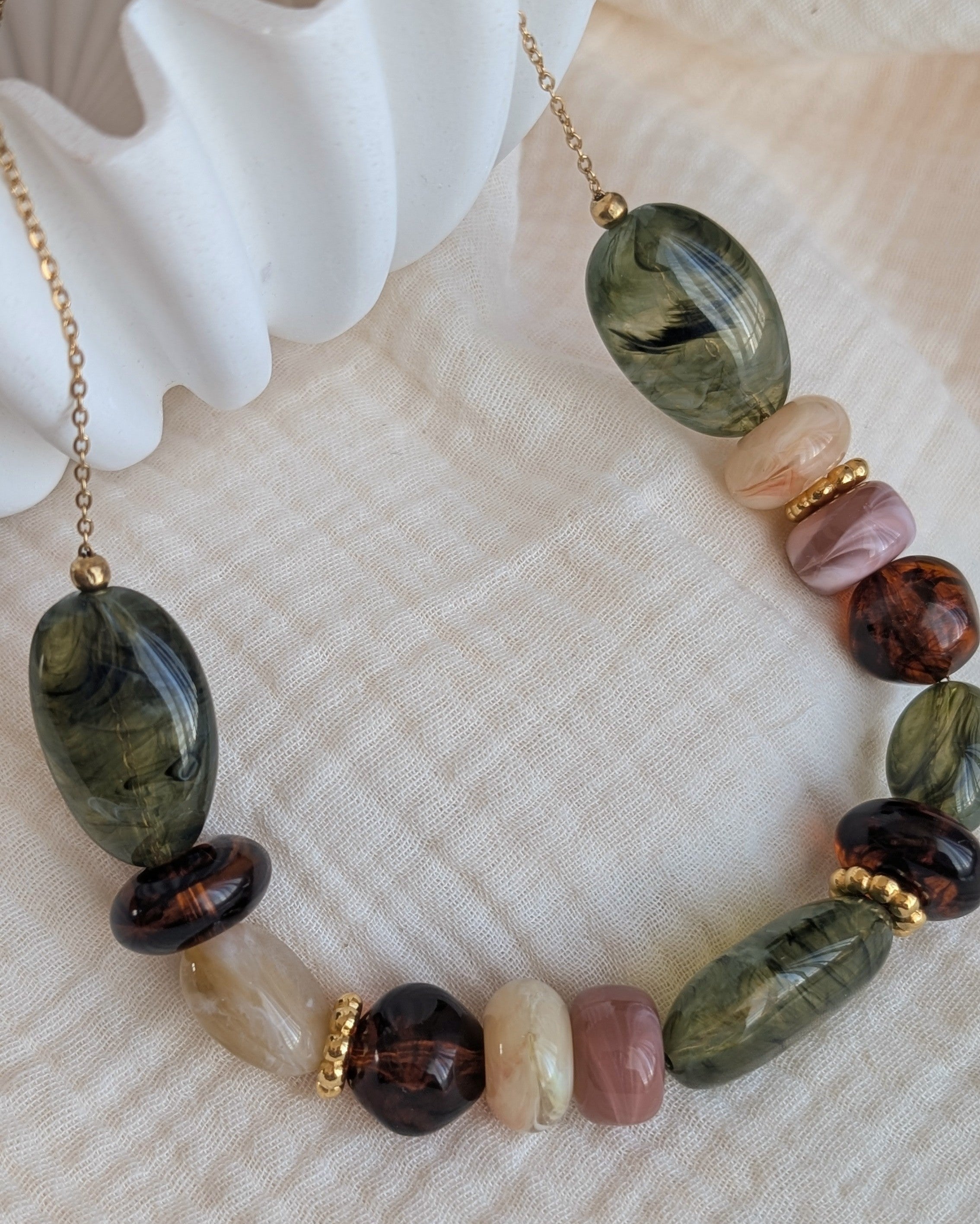 collier GABIE nuances de vert et d'ambre sur fond de gaze de coton. Perles en résine irrégulières enfilées sur chaîne maille forçat. Création artisanale La Tête dans les Nétoiles