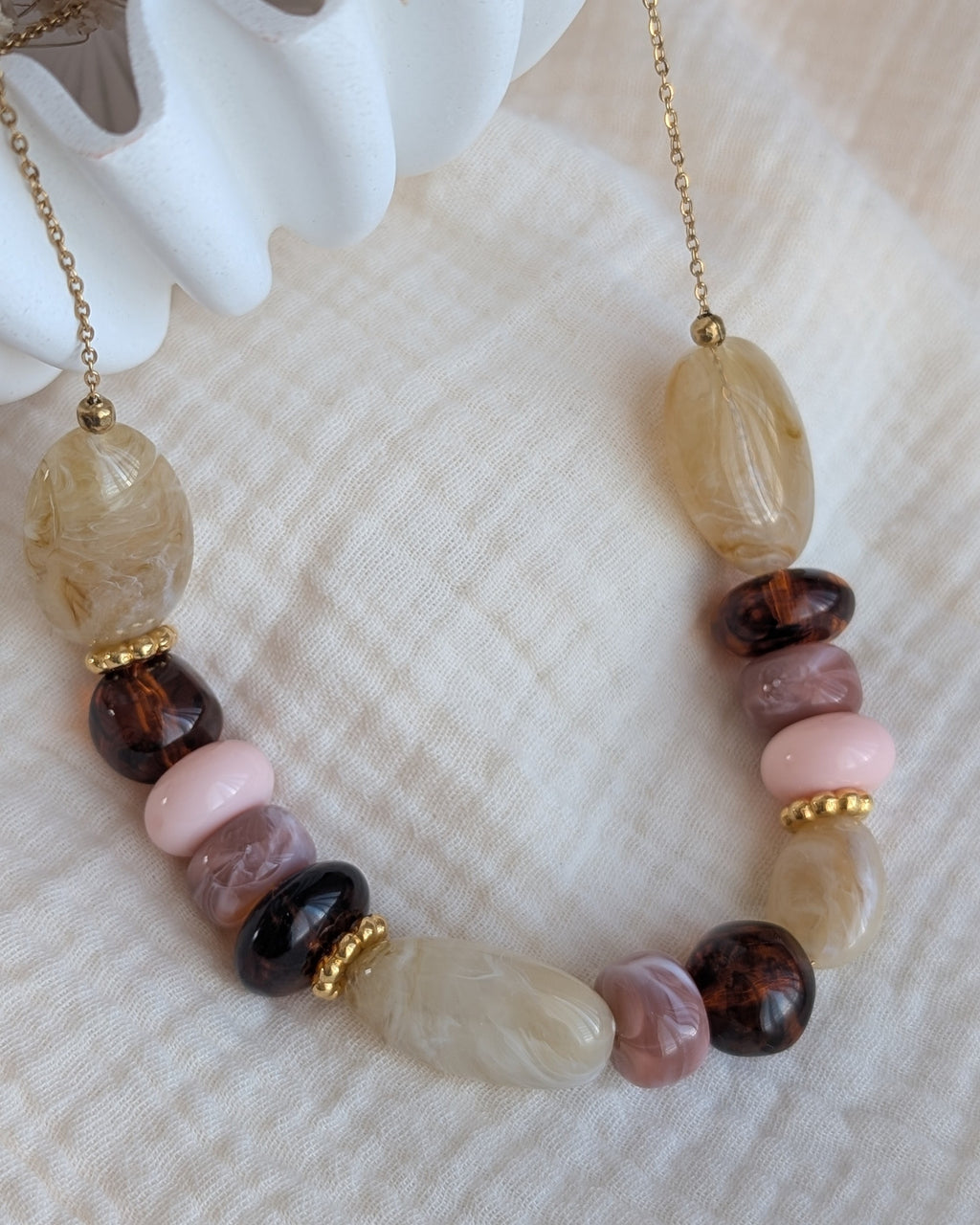 Collier GABIE posé sur gaze de coton perles ovales donuts perles irregulieres couleurs ambrée crème rose poudre nuances de rose perles irrégulières perles en résine . Création artisanale La Tête dans les Nétoiles