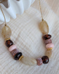 Collier GABIE posé sur gaze de coton perles ovales donuts perles irregulieres couleurs ambrée crème rose poudre nuances de rose perles irrégulières perles en résine . Création artisanale La Tête dans les Nétoiles