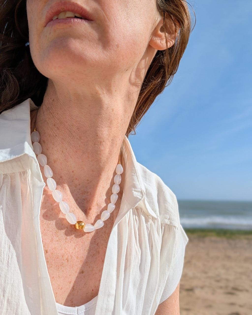Collier Louison porté par une femme coloris blanc opale avec une blouse blanche. Création La Tête dans les nétoiles