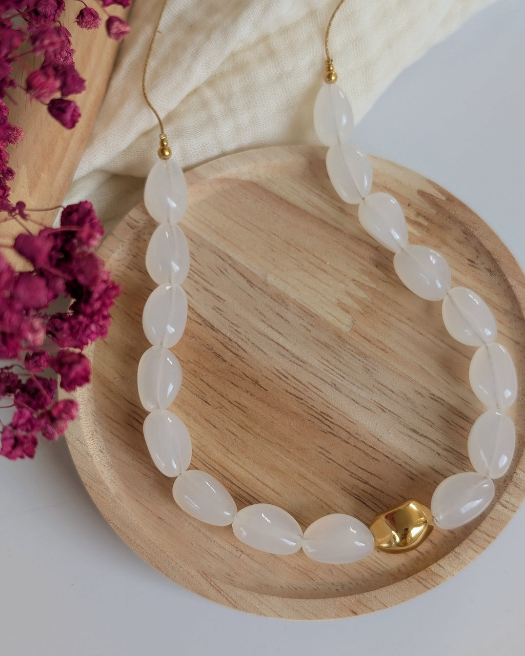 Collier Louison coloris blanc opale posé sur rondin en bois. Création La Tête dans les Nétoiles