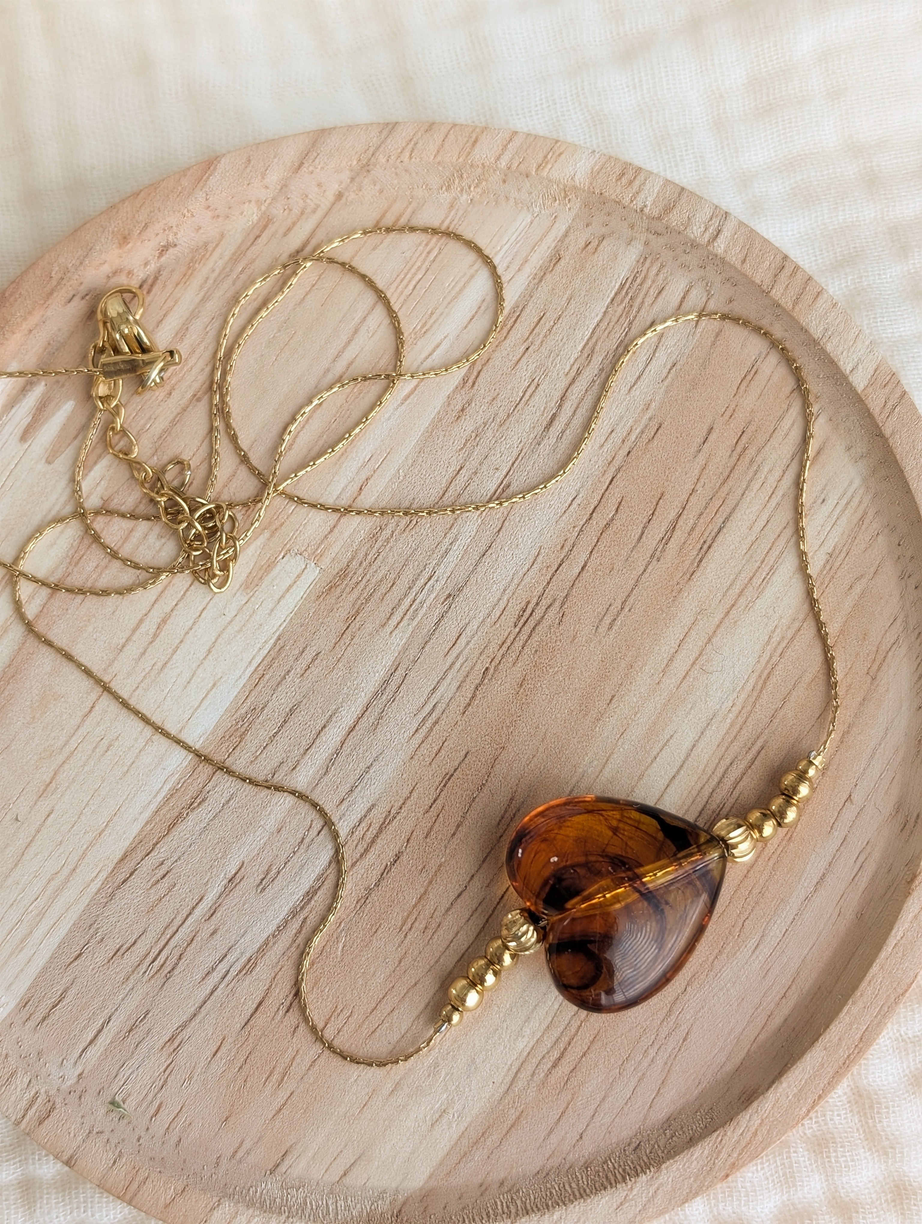 Collier MARCELLE coeur en résine ambré caramel marbré sur chaîne maille en serpentine en acier inoxydable doré. Créations artisanales La Tête dans les Nétoiles