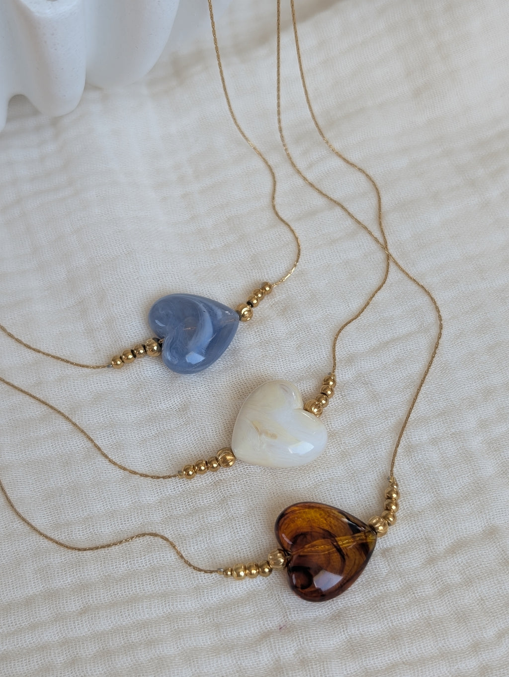 Collier Marcelle coeur disponible en 3 coloris. Bleu nuage crème et ambré caramel. Sur maille fine serpentine résistante en acier inoxydable. Créations artisanales La Tête dans les Nétoiles