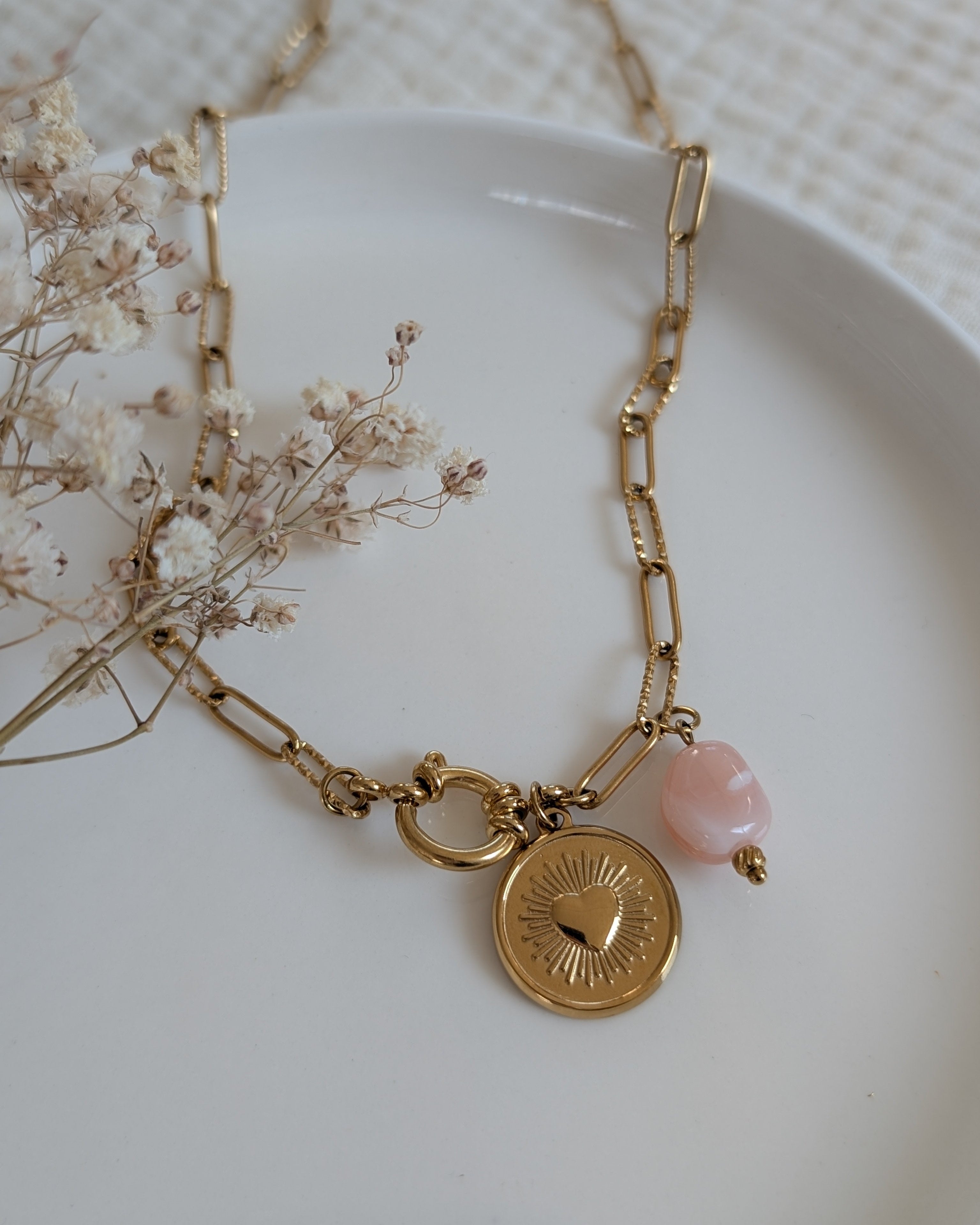 Collier Nahée coeur radiant et perles en résine sur chaîne trombone. Posé sur coupelle. Création La Tête dans les Nétoiles