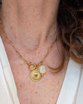 Collier Nahée pendentif coeur radiant sur chaîne trombone en acier inoxydable doré. Porté par une femme avec blouse blanche. Créations artisanales La Tête dans les Nétoiles.