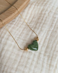 Collier Aimée perle coeur en résine vert kaki et acier inoxydable doré. Posé sur plateau en bois et gaze de coton écru. Créations faits main La Tête dans les Nétoiles