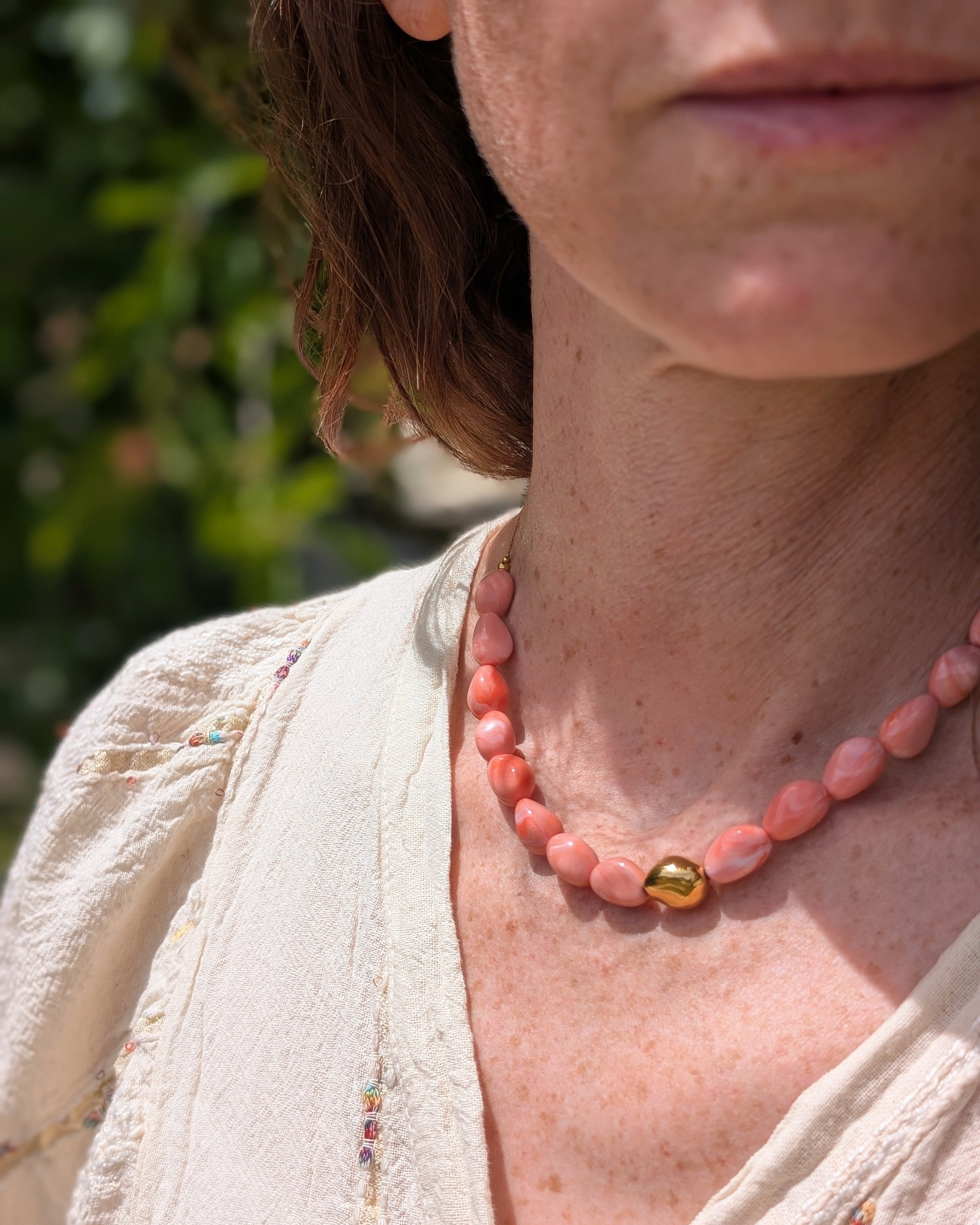 Collier Louison rose corail marbré porté par une femme. Création La Tête dans les Nétoiles