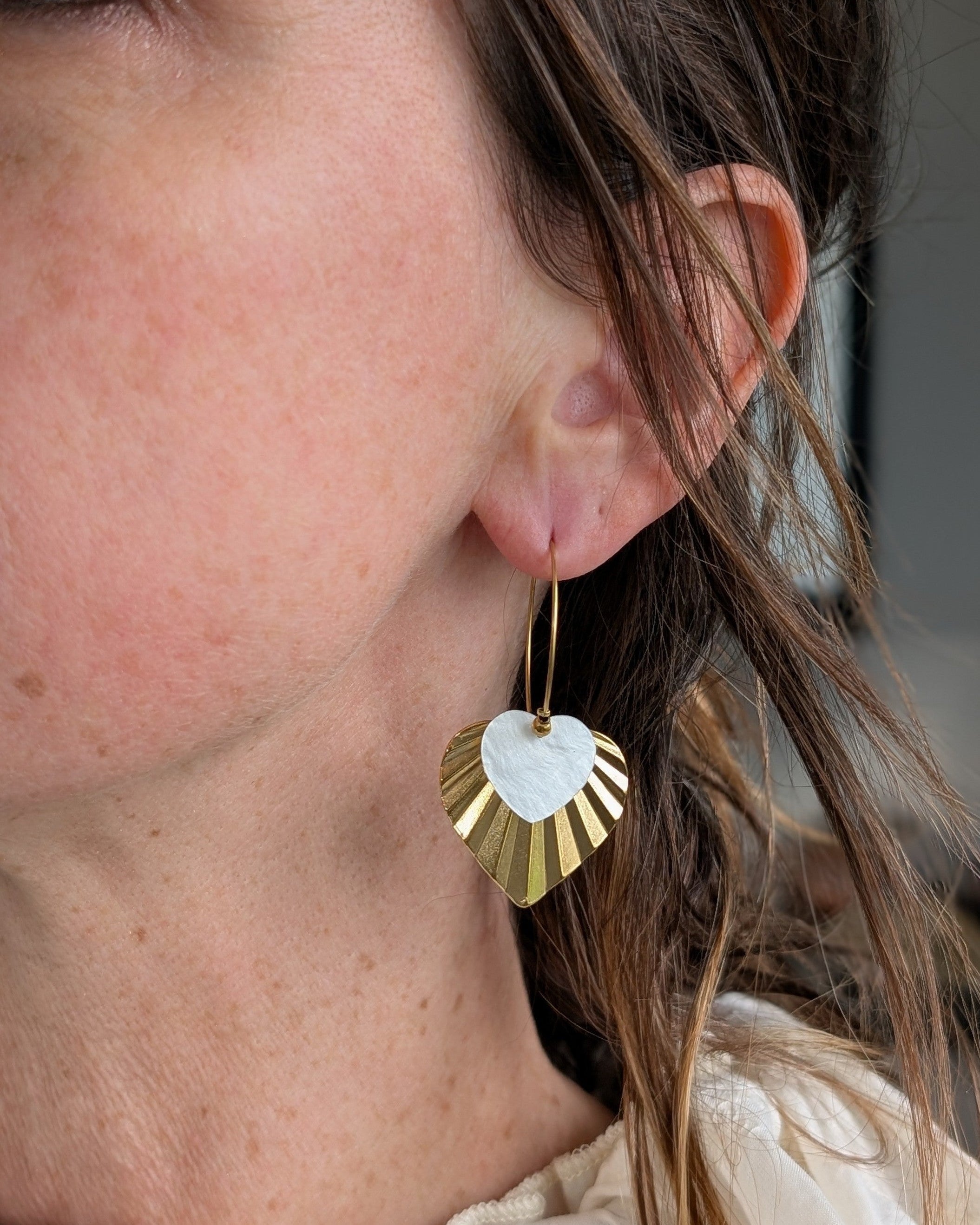 Créoles ALMA double coeur blanc et doré pendentif strié acier inoxydable doré porté par une femme. Création artisanale La Tête dans les Nétoiles