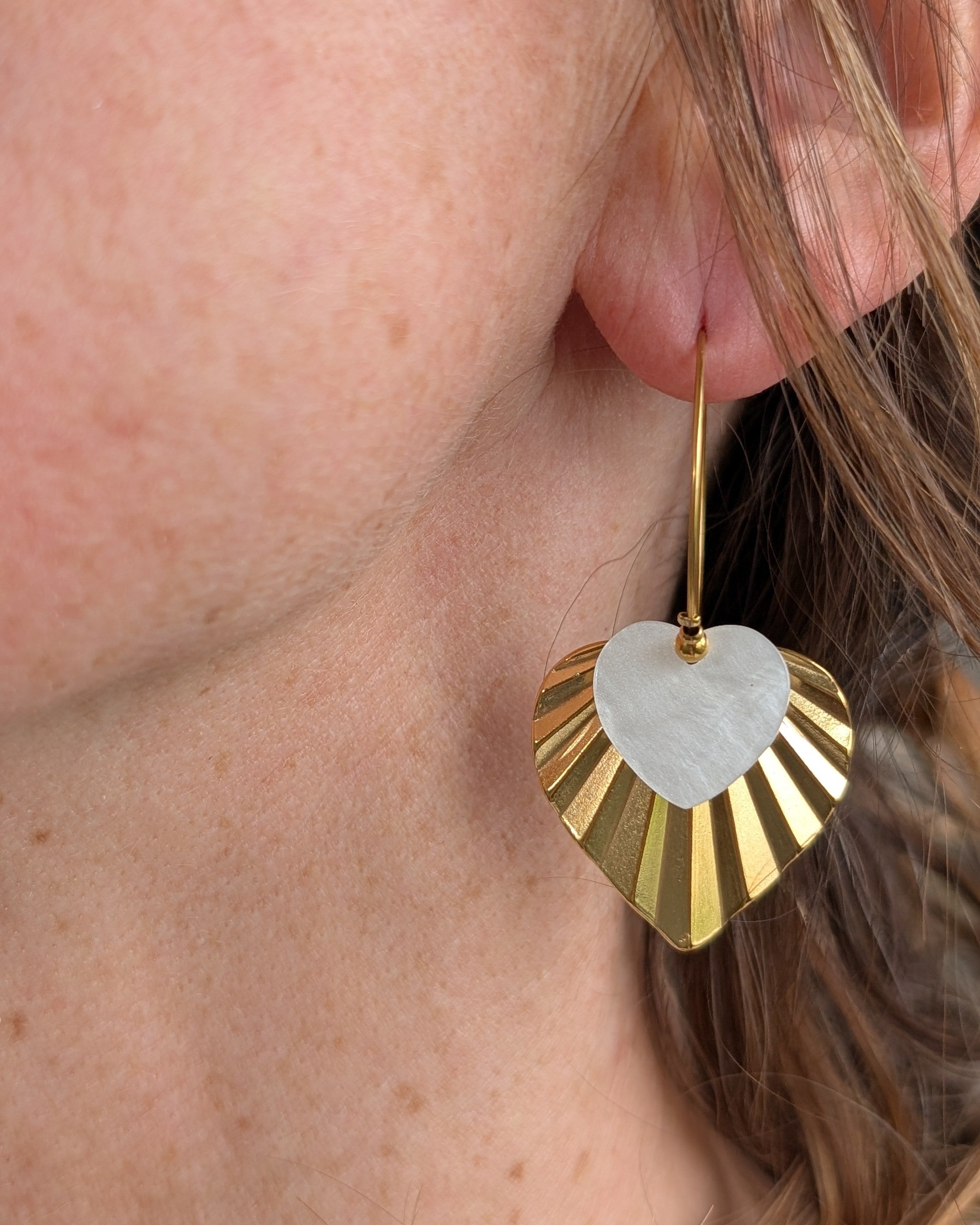 Creoles ALMA double coeur blanc et dore porte par une femme photo en gros plan. Création artisanale La Tête dans les Nétoiles