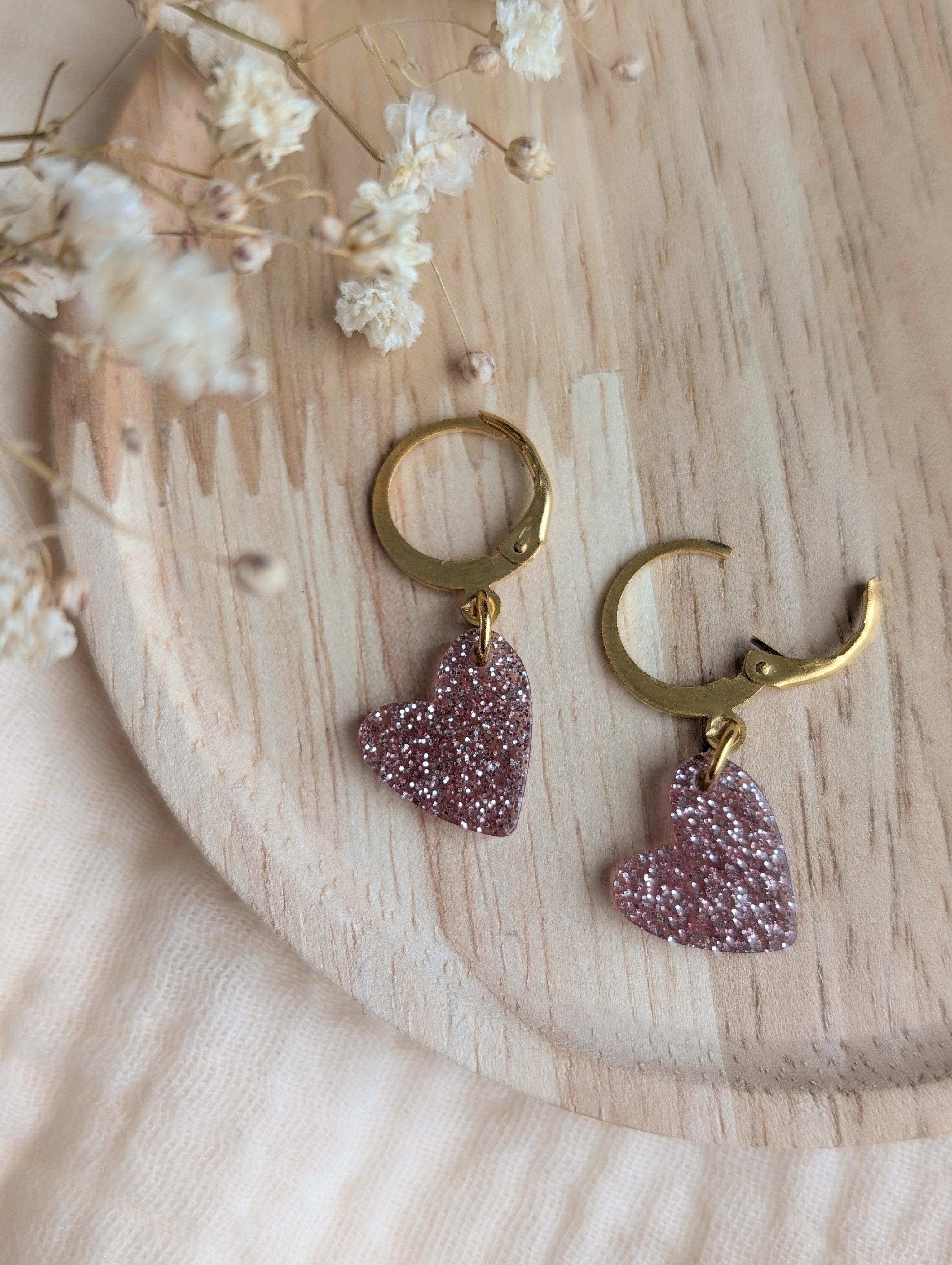 Détail des boucles d'oreilles petites filles cœur rose pailleté. Créoles ouvertes. Création artisanale La Tête dans les Nétoiles.
