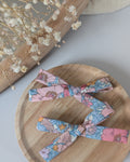 Duo de barrettes Liberty fleurs rose posé sur support en bois. Création cousu La Tête dans les Nétoiles