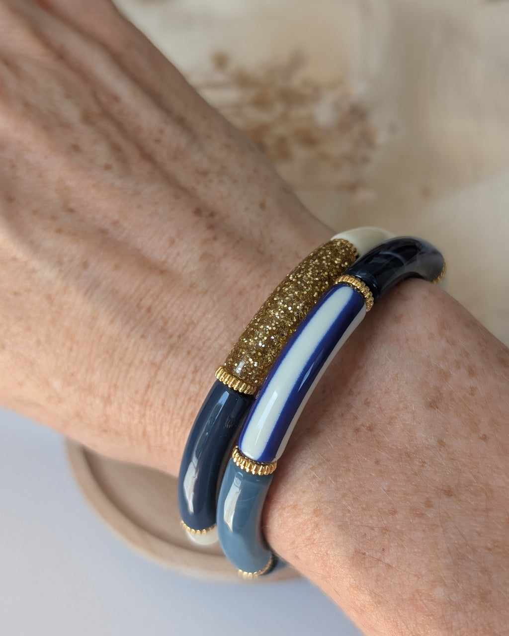 Duo de bracelets perles tube Lison rayures bleues et paillettes. Portés au poignet d'une Femme. Création artisanale La Tête dans les Nétoiles 
