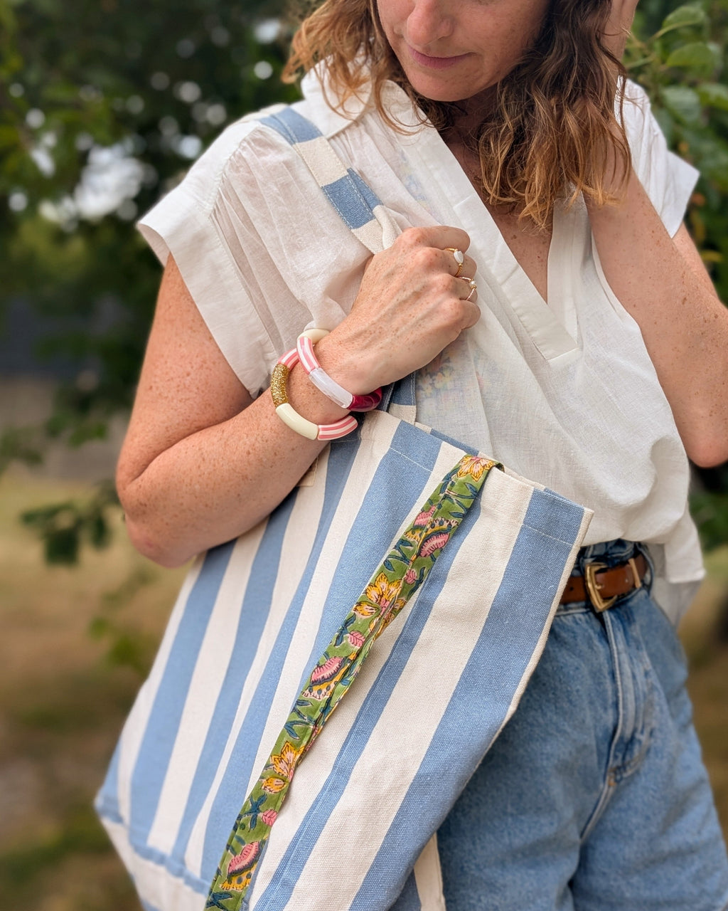 Duos de bracelets perles tube Mona à rayures rose portés par une femme. avec un sac sézane. Créations Fait main  La Tête dans les Netoiles
