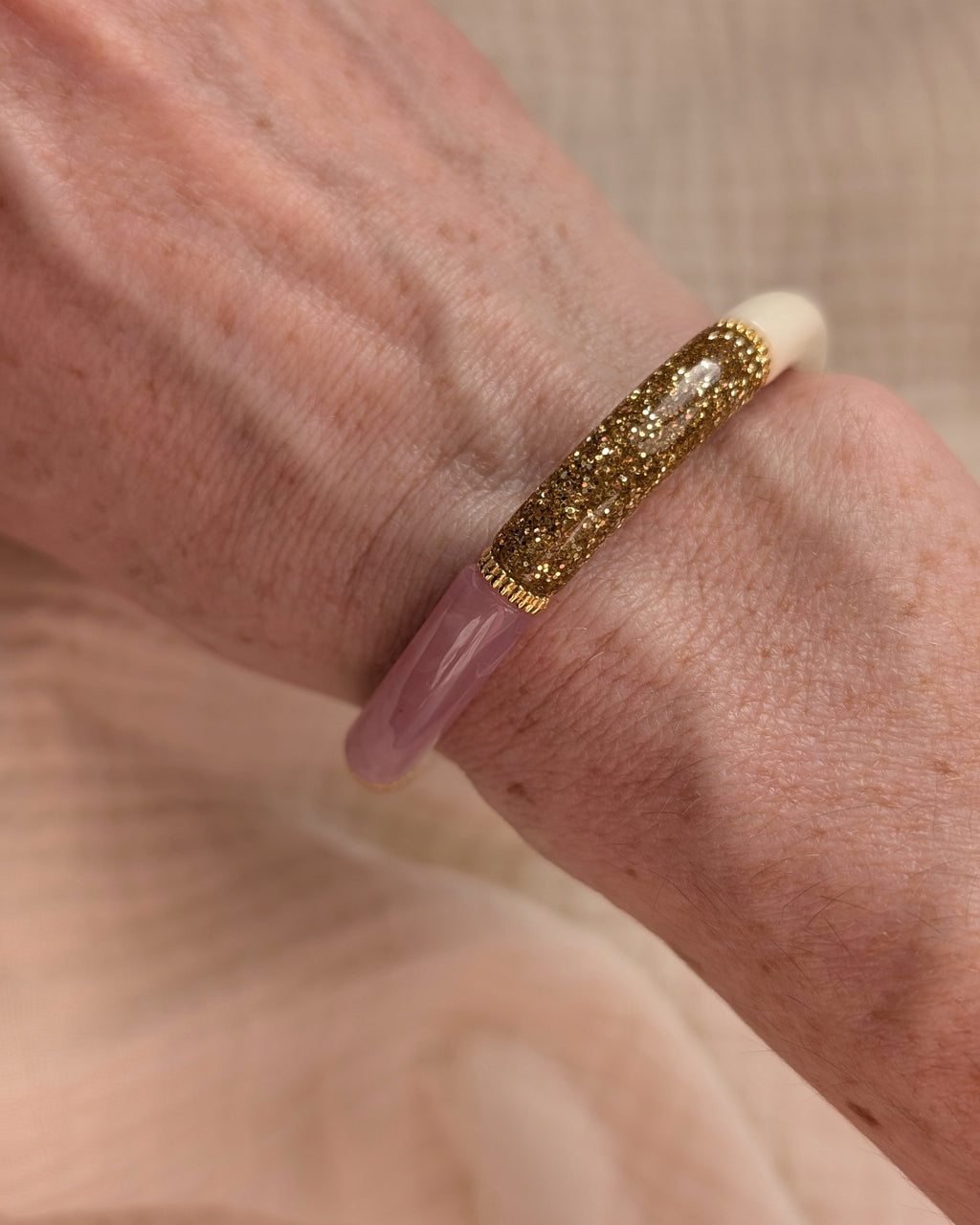 Gros plan porté sur bracelet perle tube rose tendre et glitter. Perles intercalaire doré de haute qualité. Porté au poignet d'une femme.