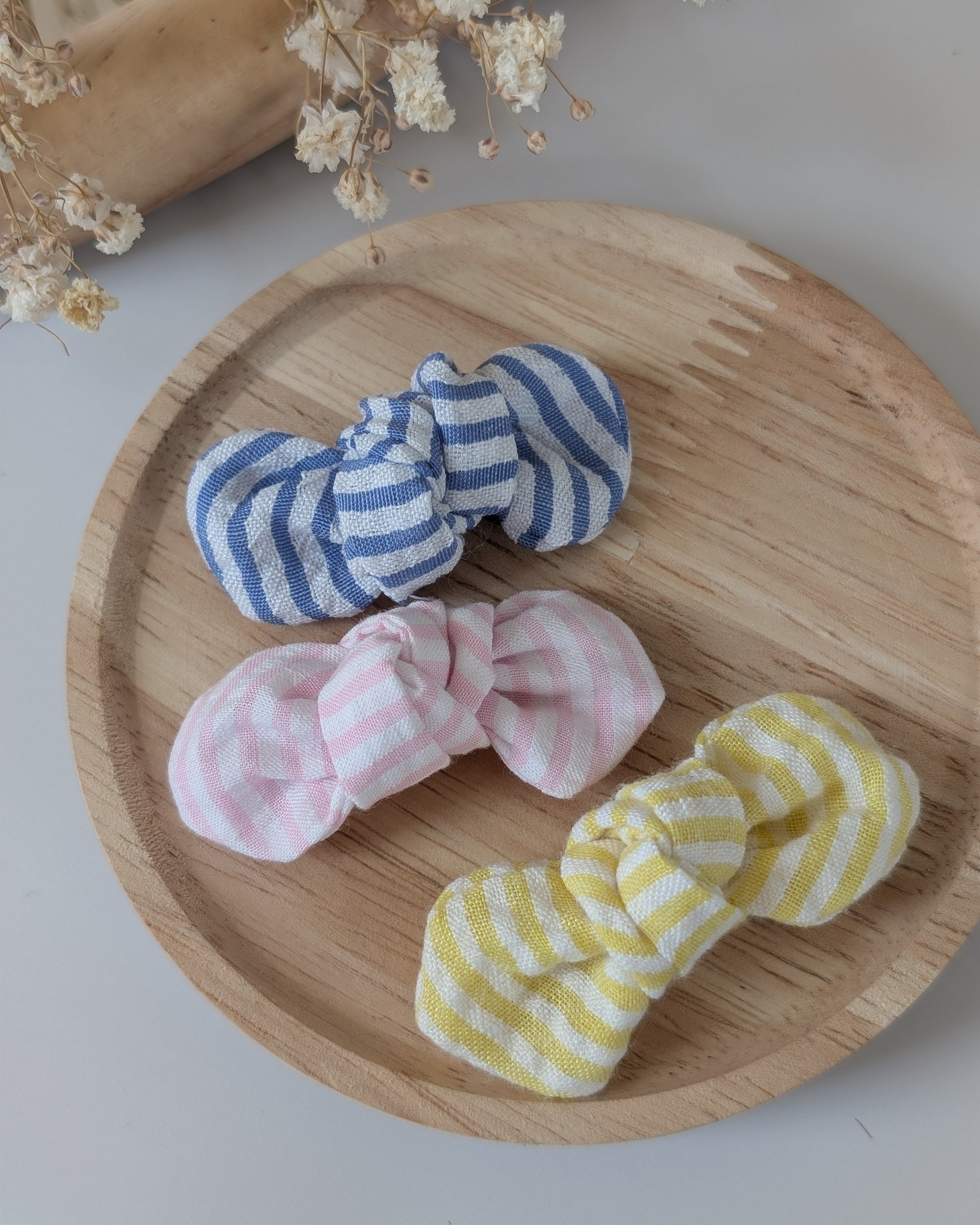 Noeuds cheveux en coton seersucker gaufré à rayures bleu, jaune et rose. Cousu main La Tête dans les Nétoiles. 
Posés sur un support en bois