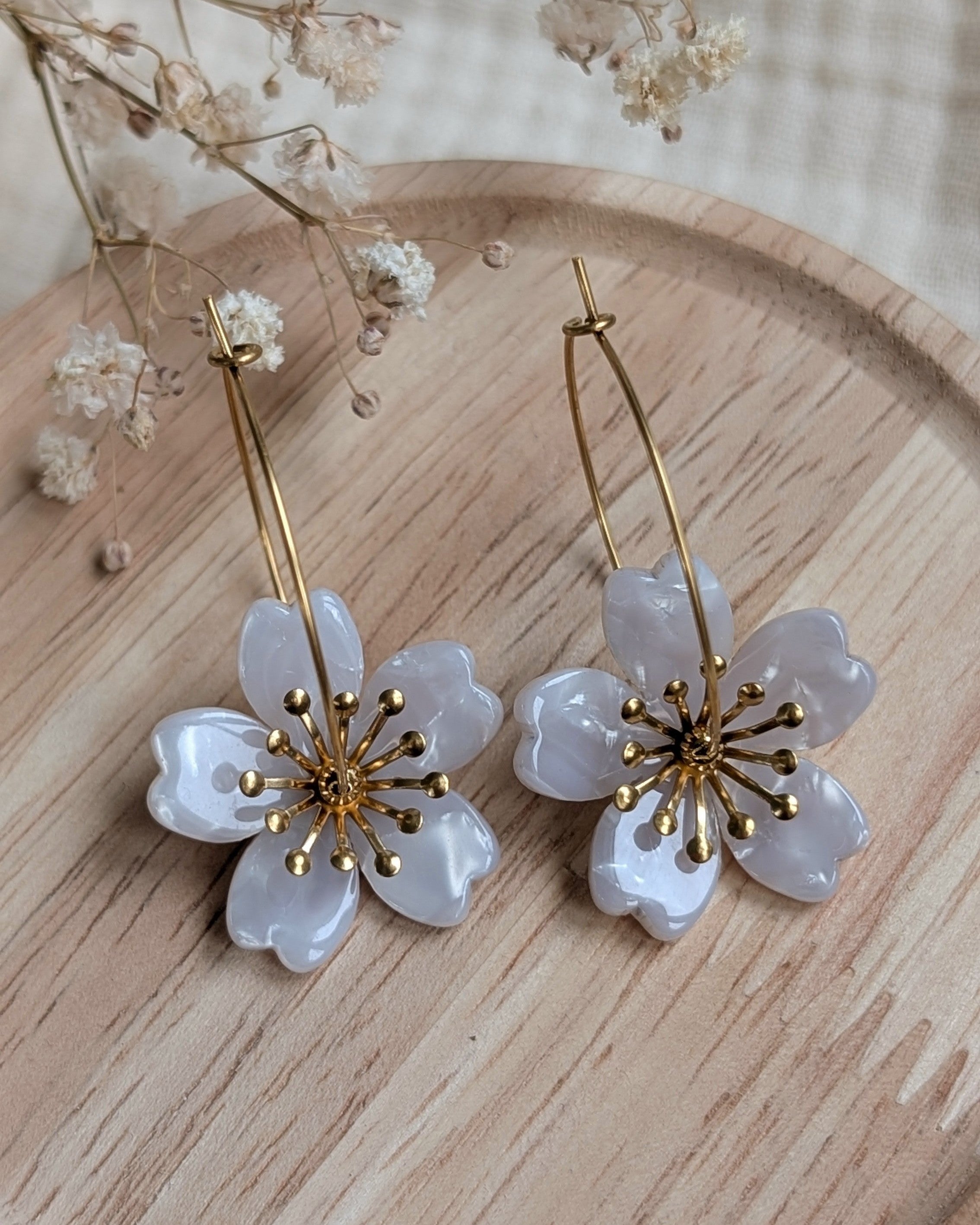 Bijou poétique Siloé blanc nacré opalin, créoles fines et fleurs délicates pour un look lumineux. Création artisanale La Tête dans les Nétoiles