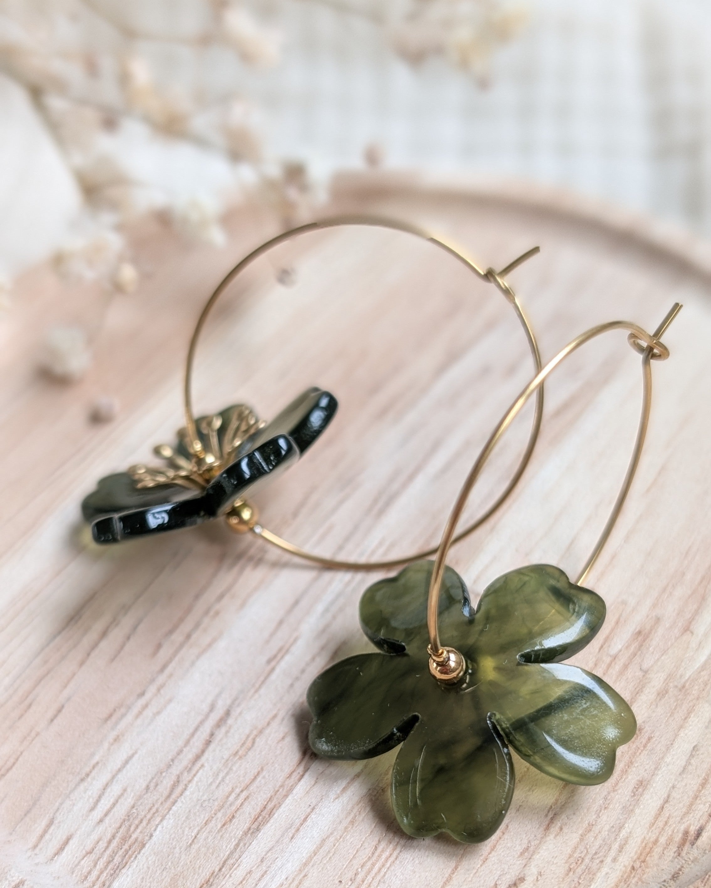 Boucles d'oreilles Siloé vert forêt posées sur bois, fleurs stylisées aux reflets organiques et pistils perlés. Vue de dos Création artisanale La Tête dans les Nétoiles