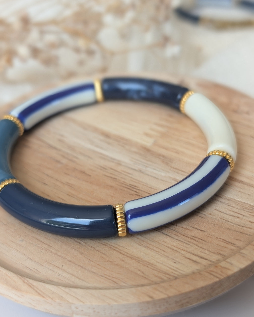 Zoom sur perles tube à rayures bleues. Posé sur un plateau en bois. Création artisanale La Tête dans les Nétoiles 