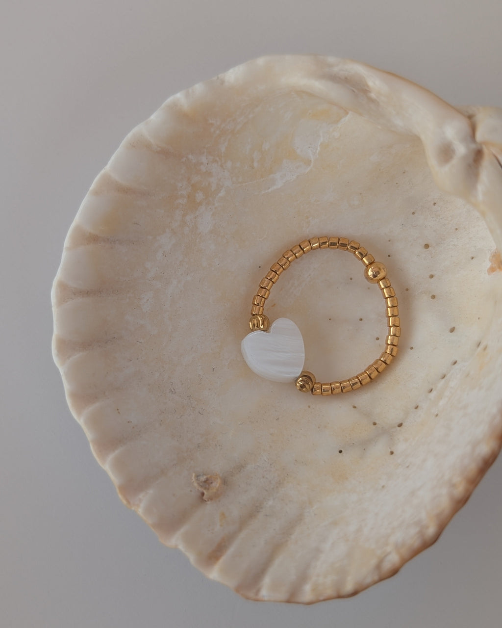 Bgaue élastique perle maxi coeur nacre et perles miyuki dorées. Posée dans un coquillage. Créations artisanales La Tête dans les Nétoiles
