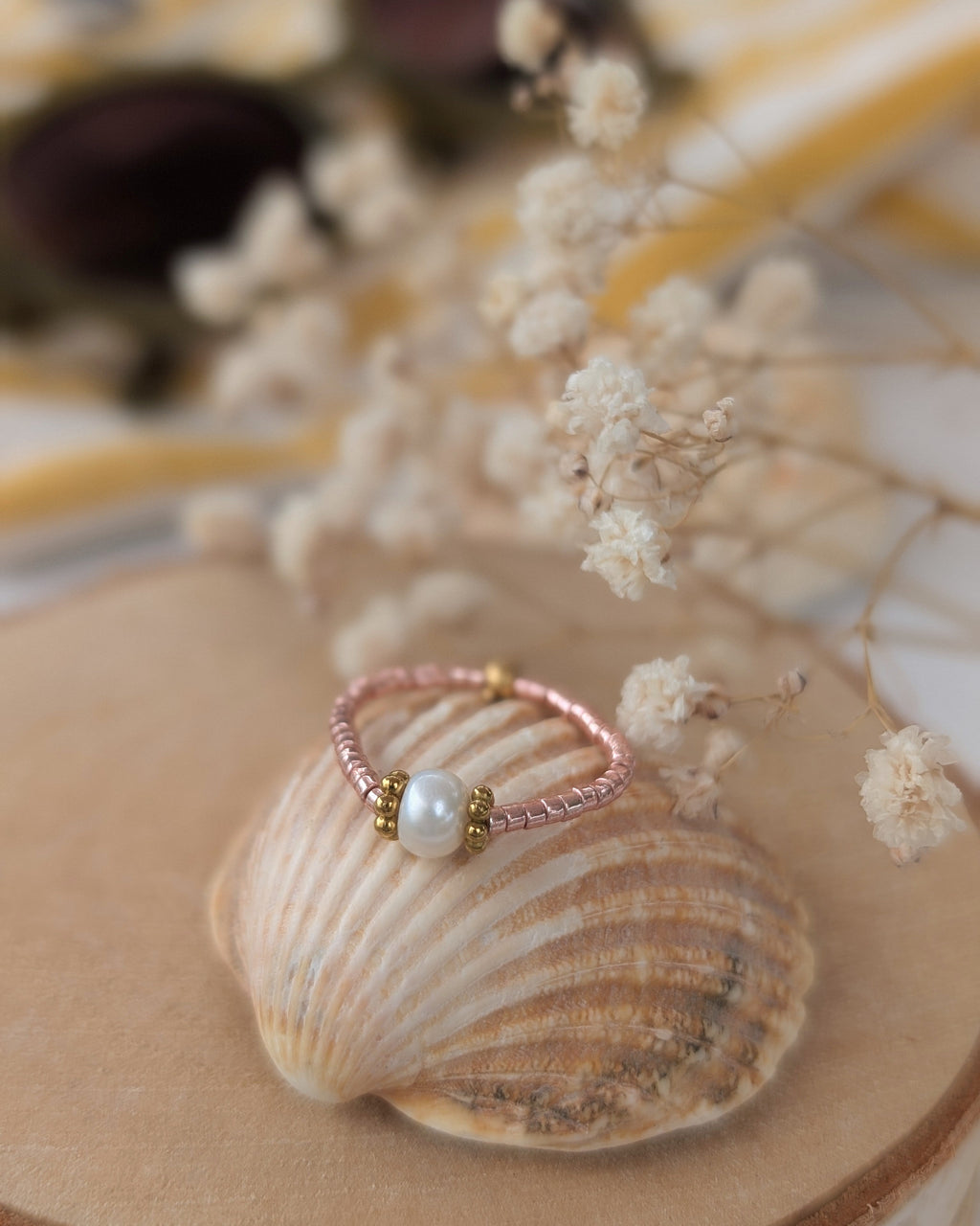 bague élastique créations artisanales La Tête dans les Nétoiles perle d'eau douce perle rondelles fleur heishi et perles miyuki. Posée sur un coquillage . 
