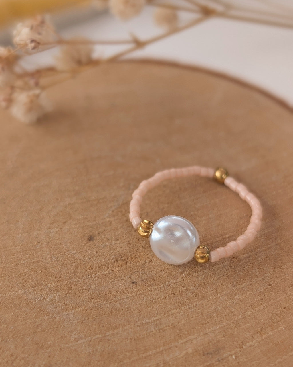 bague élastique perles miyuki et perles palet eau douce posée sur rondin de bois. Créations artisanales La Tête dans les Nétoiles