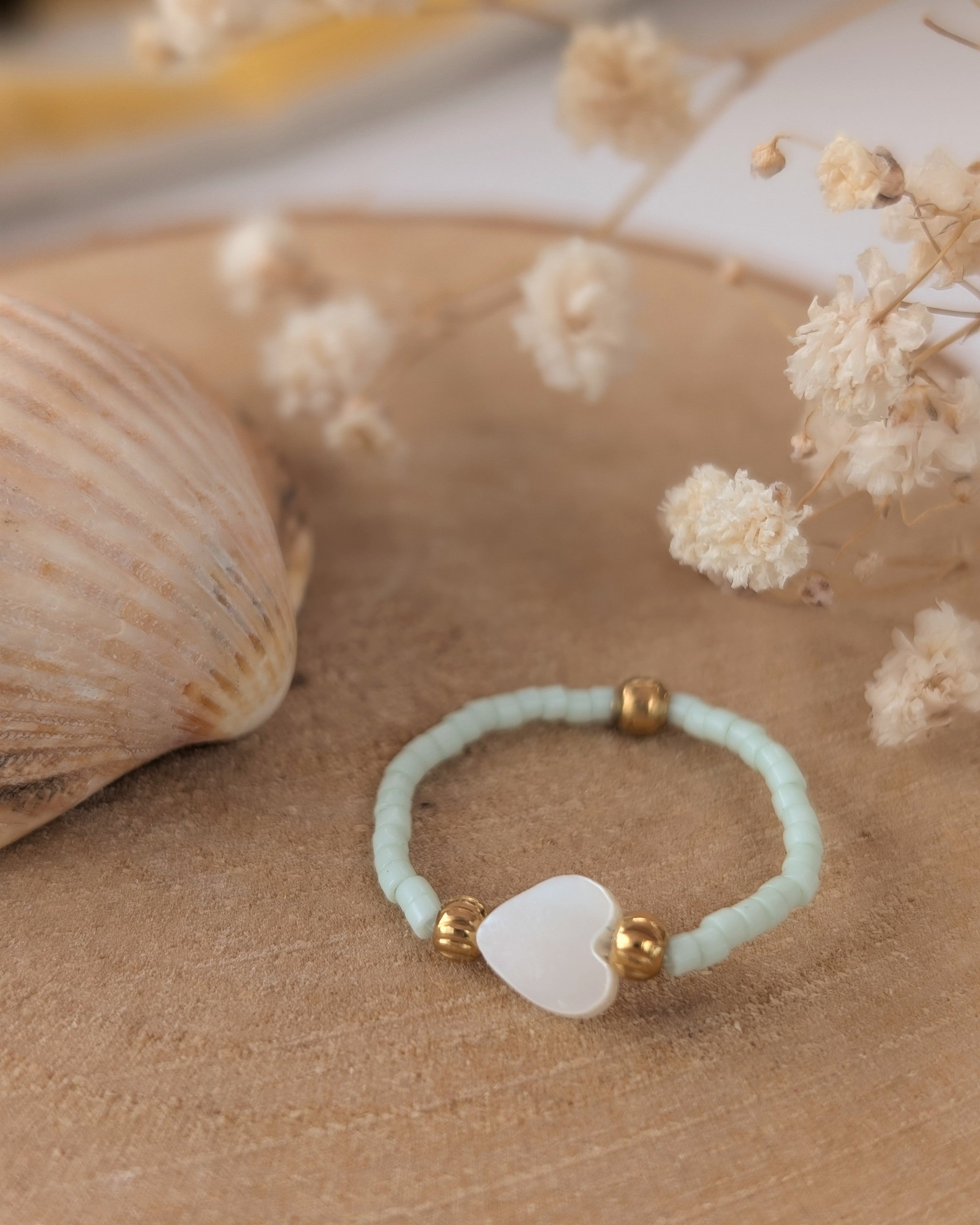 bague élastique perles miyuki et perle coeur nacré. Posée sur rondin de bois. Créations artisanales La Tête dans les Nétoiles. 