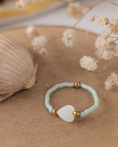 bague élastique perles miyuki et perle coeur nacré. Posée sur rondin de bois. Créations artisanales La Tête dans les Nétoiles. 
