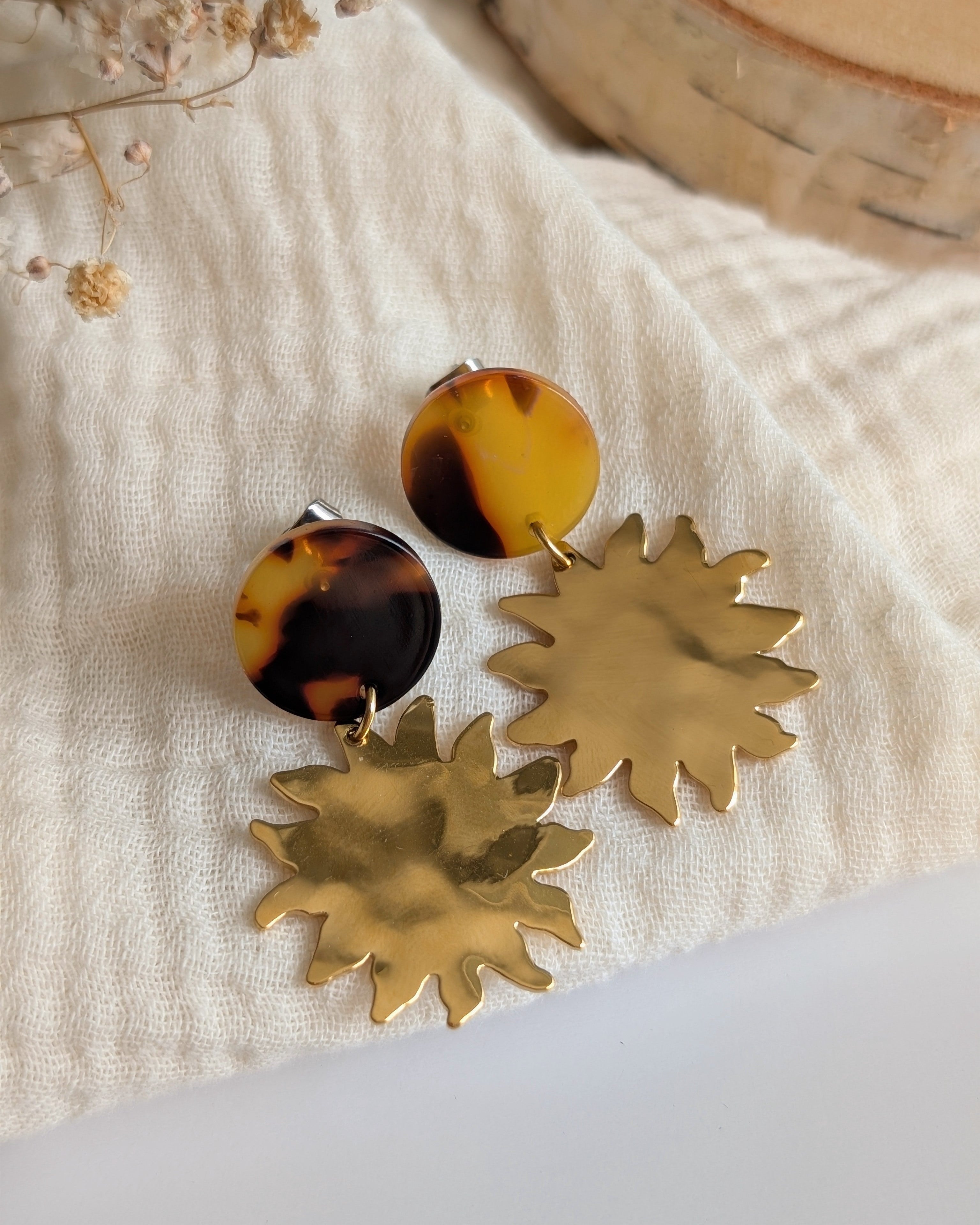 Boucles d'oreilles Soline et écaille de tortue pendentif soleil posées sur gaze de coton. Création La Tête dans les Nétoiles